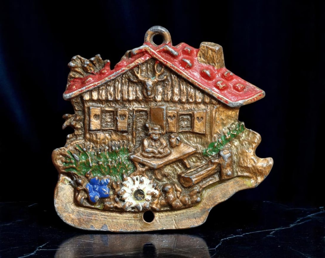 GERMANY: Alpine Rustic Life - Hand-Painted Bavarian Chalet Plaque, Undated, 50mm: A delightful homage to rural Bavarian culture, this vibrantly painted cast medal showcases a quintessential alpine scene. The stylized chalet, rendered in relief with red-shingled roof and wood-textur