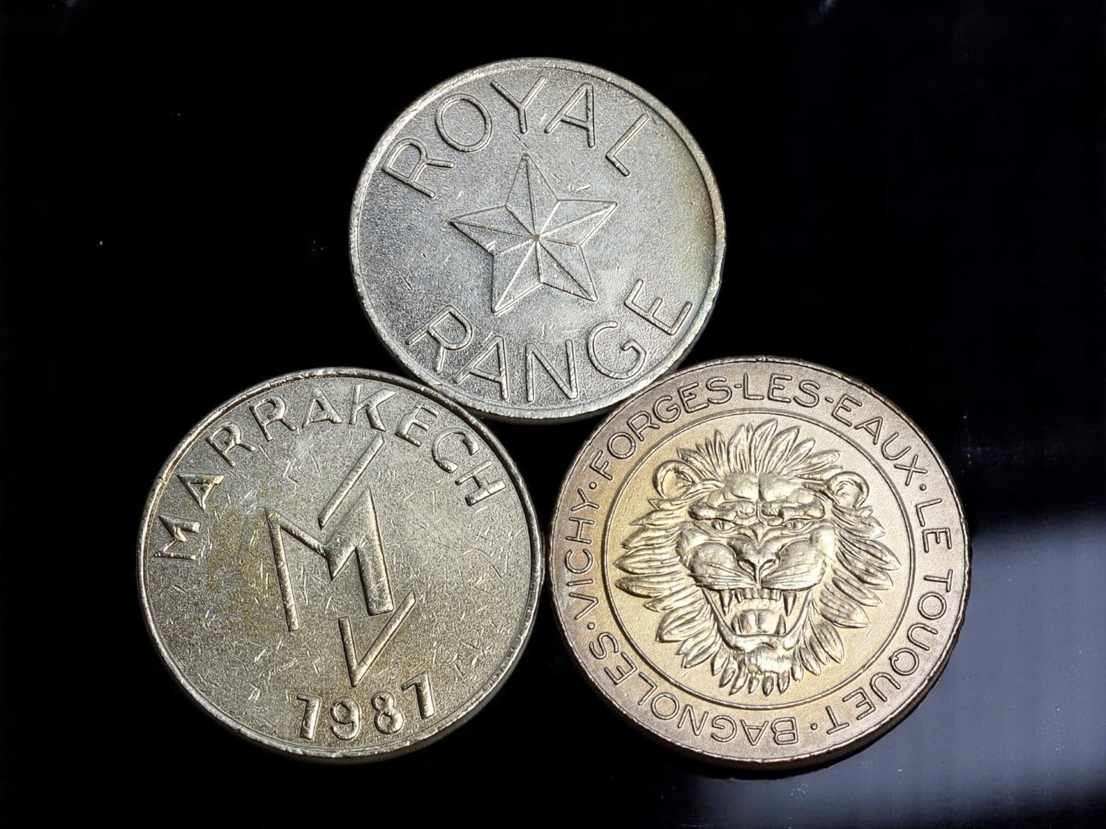 FRANCE/MOROCCO: Resort and Gaming Culture - Casino and Golf Range Token Trio, c. 1980s, 26-28mm: This compelling trio of large-format brass and nickel-alloy tokens embodies the vibrant leisure and gaming culture of France and Morocco during the late 20th century. The standout is the boldly struck