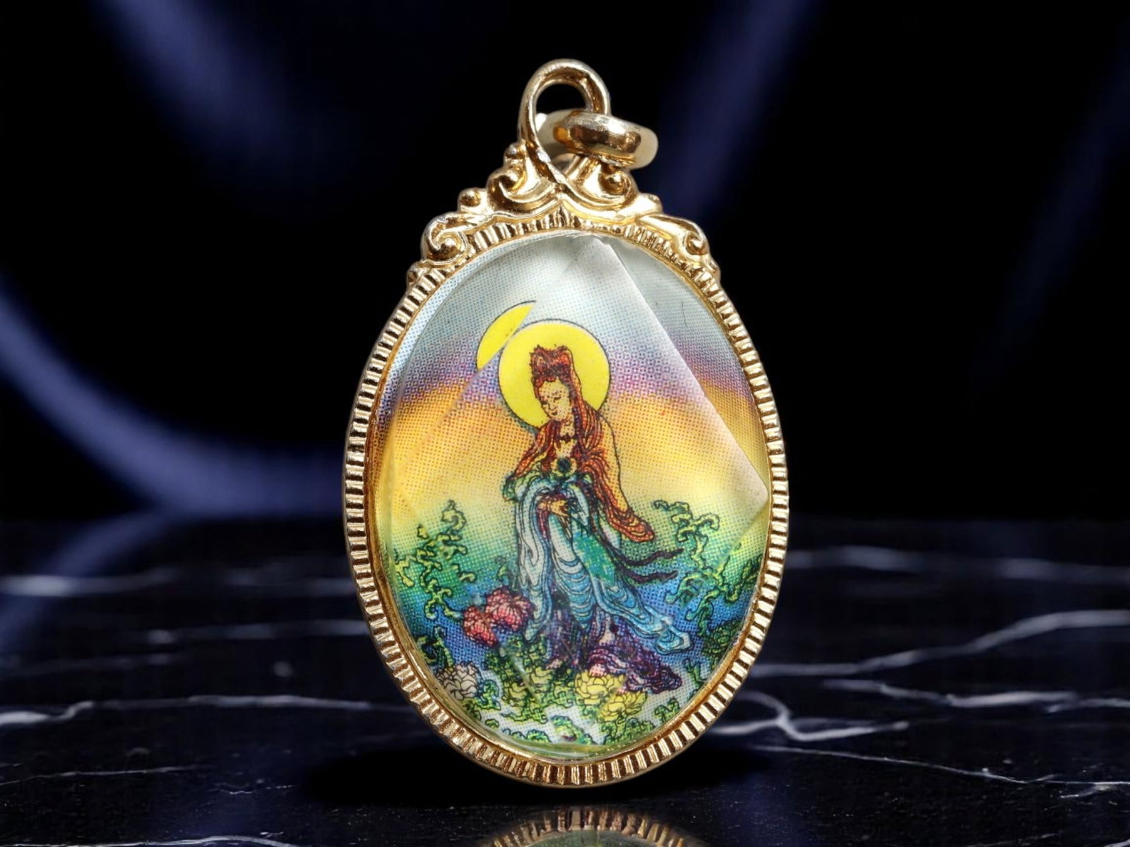 GERMANY: Kwan Yin - Eastern Mercy Goddess Devotional Pendant, c.1950s, 27x16mm: This richly hued devotional pendant features a serene depiction of Kwan Yin, the Eastern bodhisattva of compassion, poised in flowing robes amidst stylized waves and blooming flora. Framed in an ornat