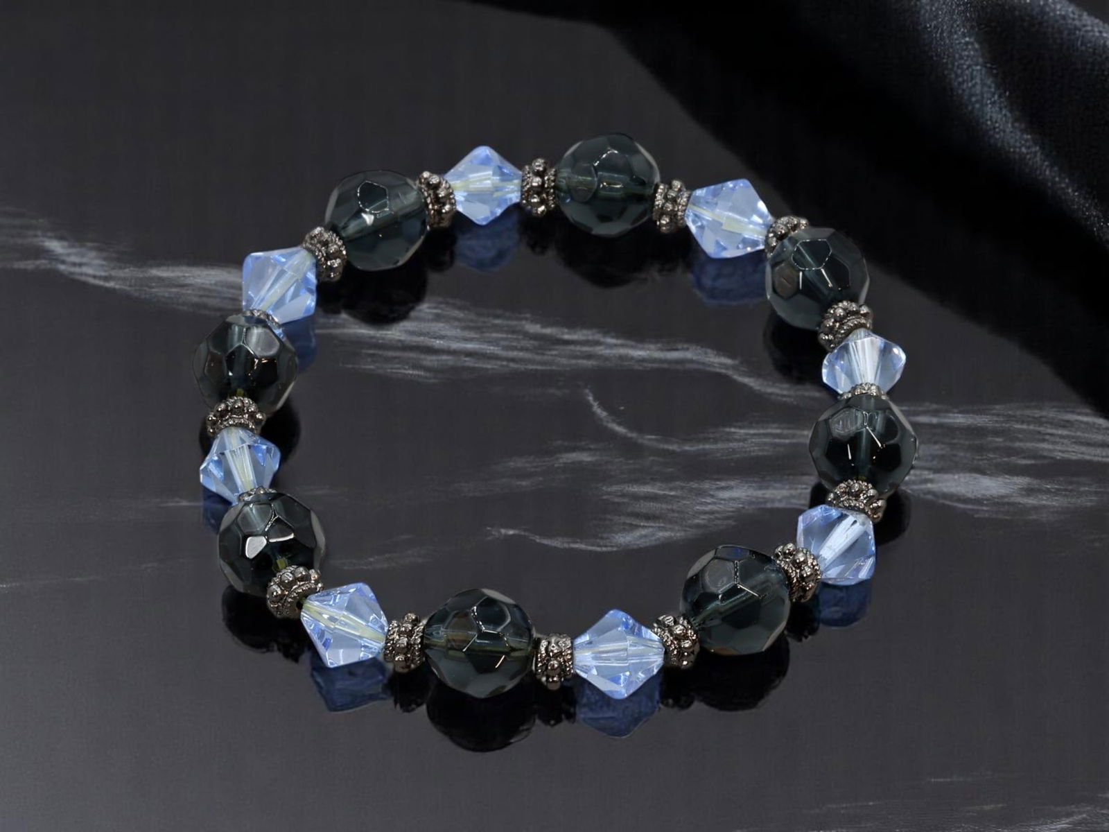 ARTISTIC MODERN ESTATE: Beaded Bracelet - Faceted Blue & Smoky Beads, Spacer Accents: From an estate jewelry collection, this artistic modern beaded bracelet offers a sleek and striking design. The stretch strand alternates between faceted smoky charcoal-like beads and soft icy blue cr