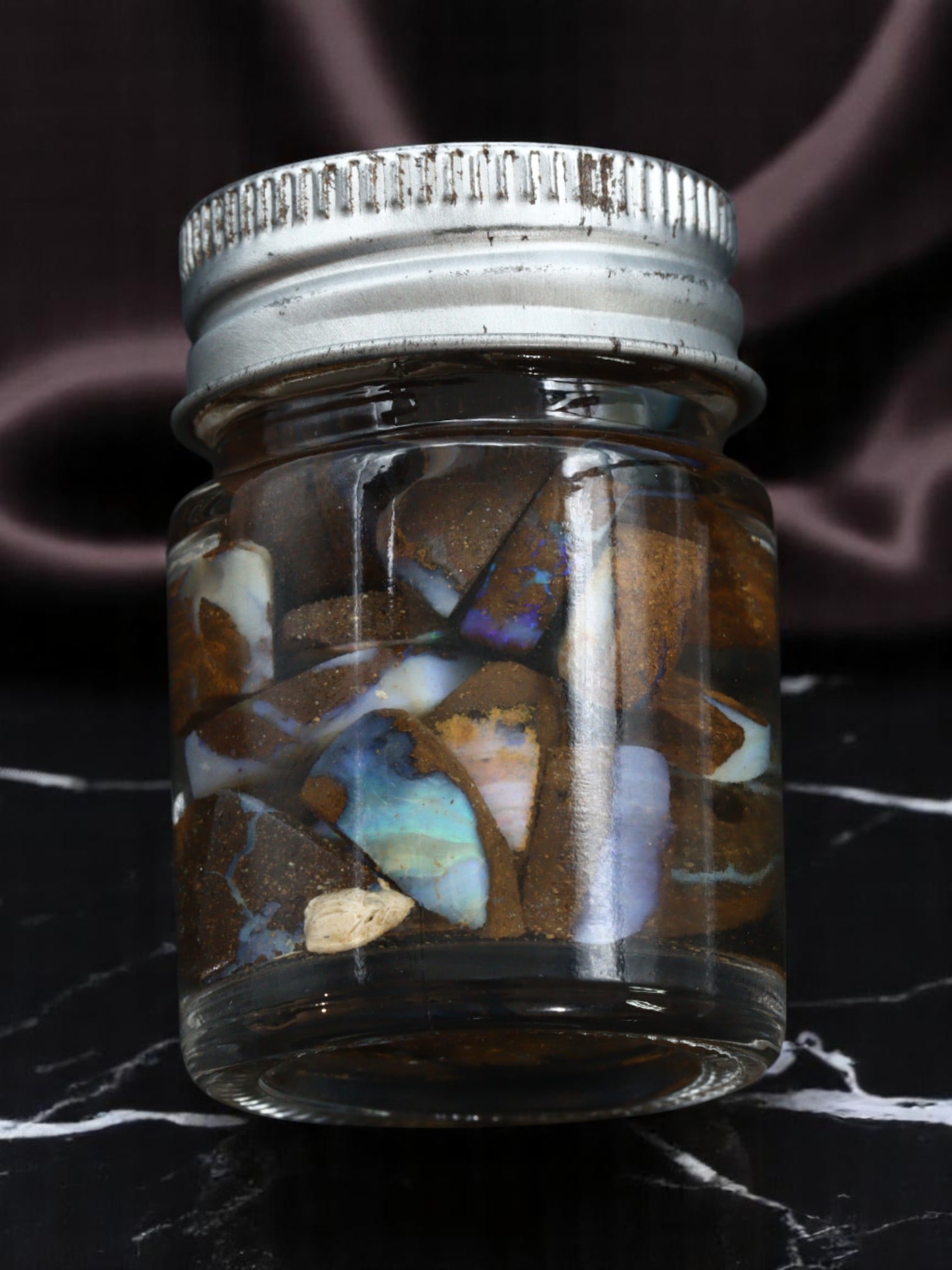 Yowah Boulder Opal Specimen Jar - Natural Rubs, Assorted Matrix Patterns (Jar Size 4.5x2.5cm): A fascinating collector's jar filled with assorted natural Yowah boulder opal rub specimens, this lot offers a vibrant display of earthy matrix and opal-effect color flashes. The jar holds an array of