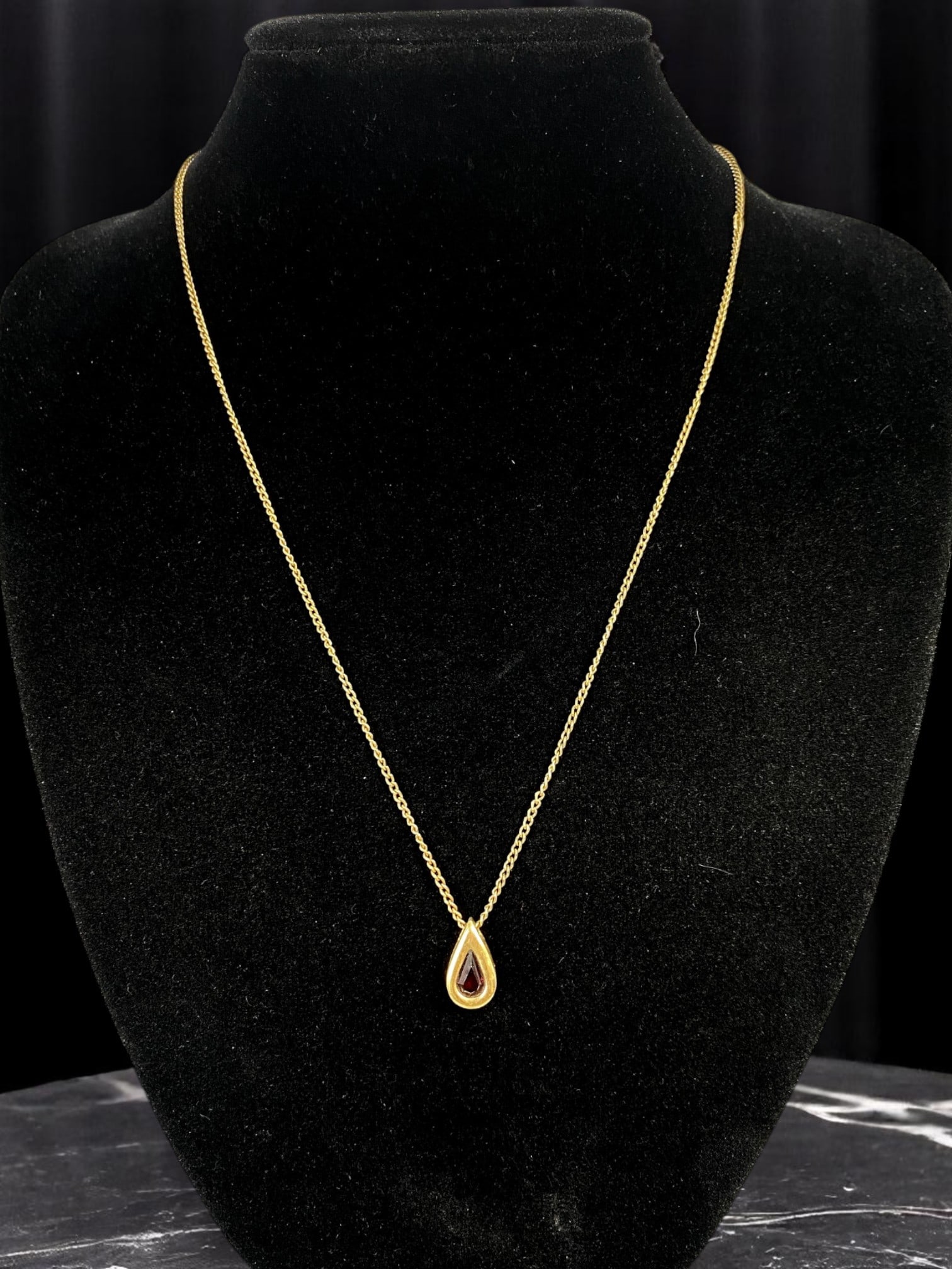 AVON - Classic Elegance Teardrop Pendant Necklace, 50cm: Exuding timeless grace, this refined 50cm necklace by Avon features a delicate gold-tone chain accented by an exquisite teardrop-shaped pendant. At its center, a rich ruby-colored stone radiates warmt