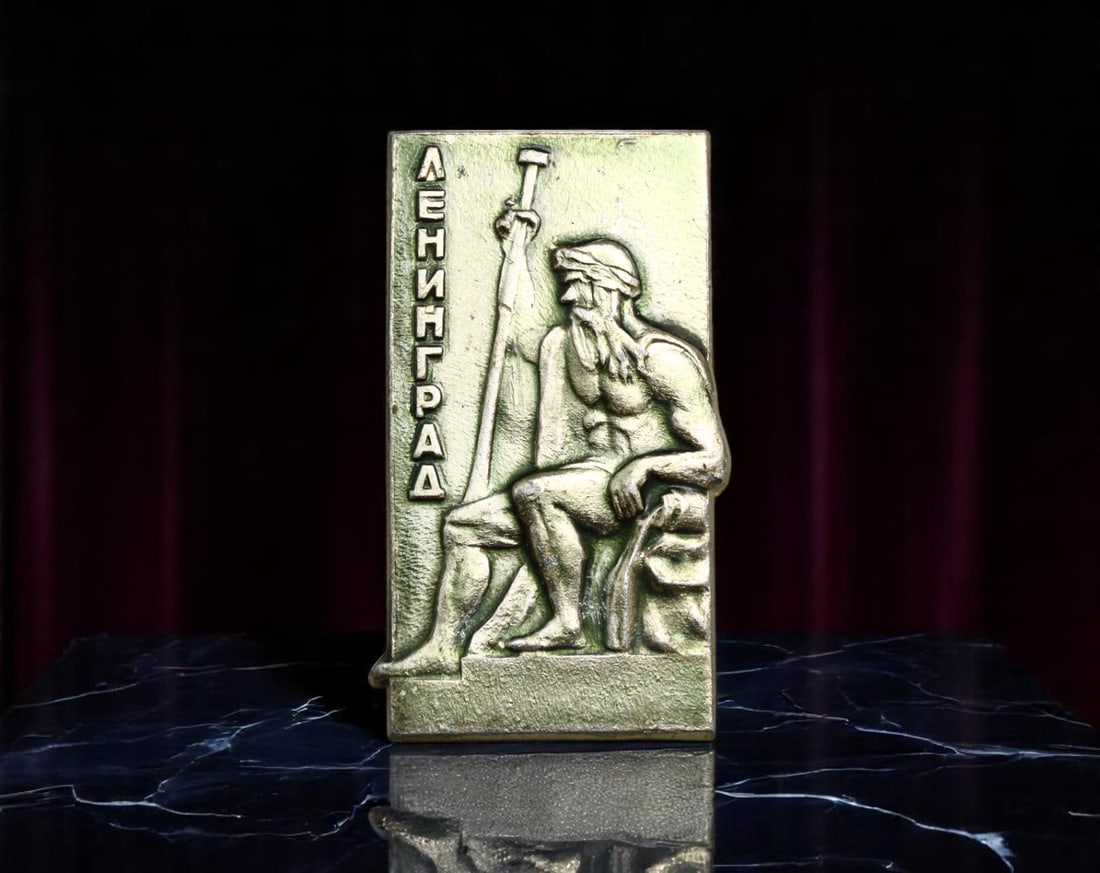 USSR: Leningrad - Neptune and Naval Power Commemorative Badge, circa 1970s, 34x18mm: This evocative 34x18mm gilt badge pays tribute to Leningrad, the Soviet name for the historic city of Saint Petersburg, by featuring a muscular, bearded Neptune figure seated with a trident. Represent