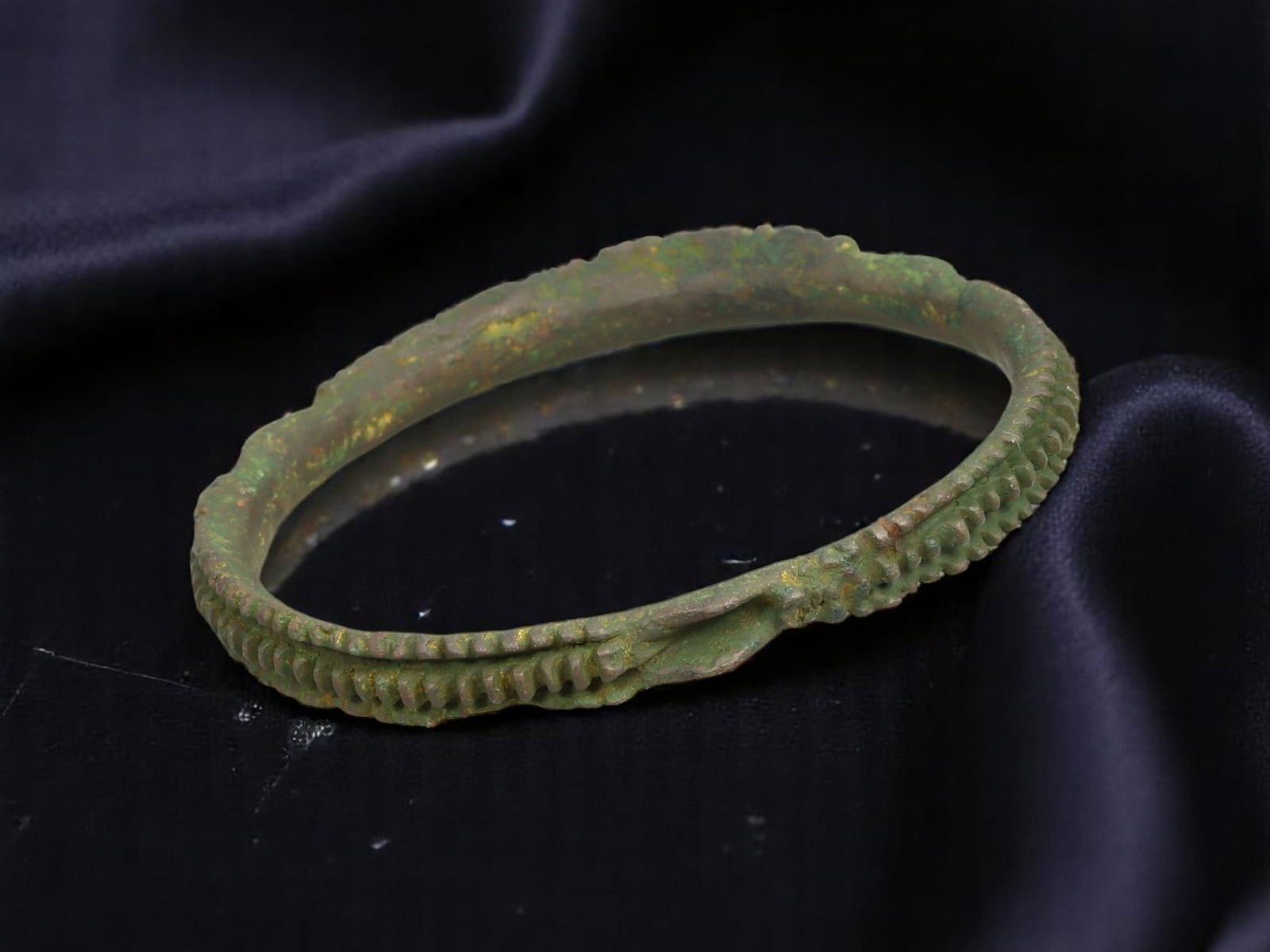 LATE ROMAN / EARLY BYZANTINE Textured Chevron-Edge Bronze Bracelet, 7.7 cm: A striking example of Late Antique bronze ornamentation, this rigid bracelet features sharply defined chevron-edge ridging, creating a distinctive serrated silhouette. The surface is adorned with tigh