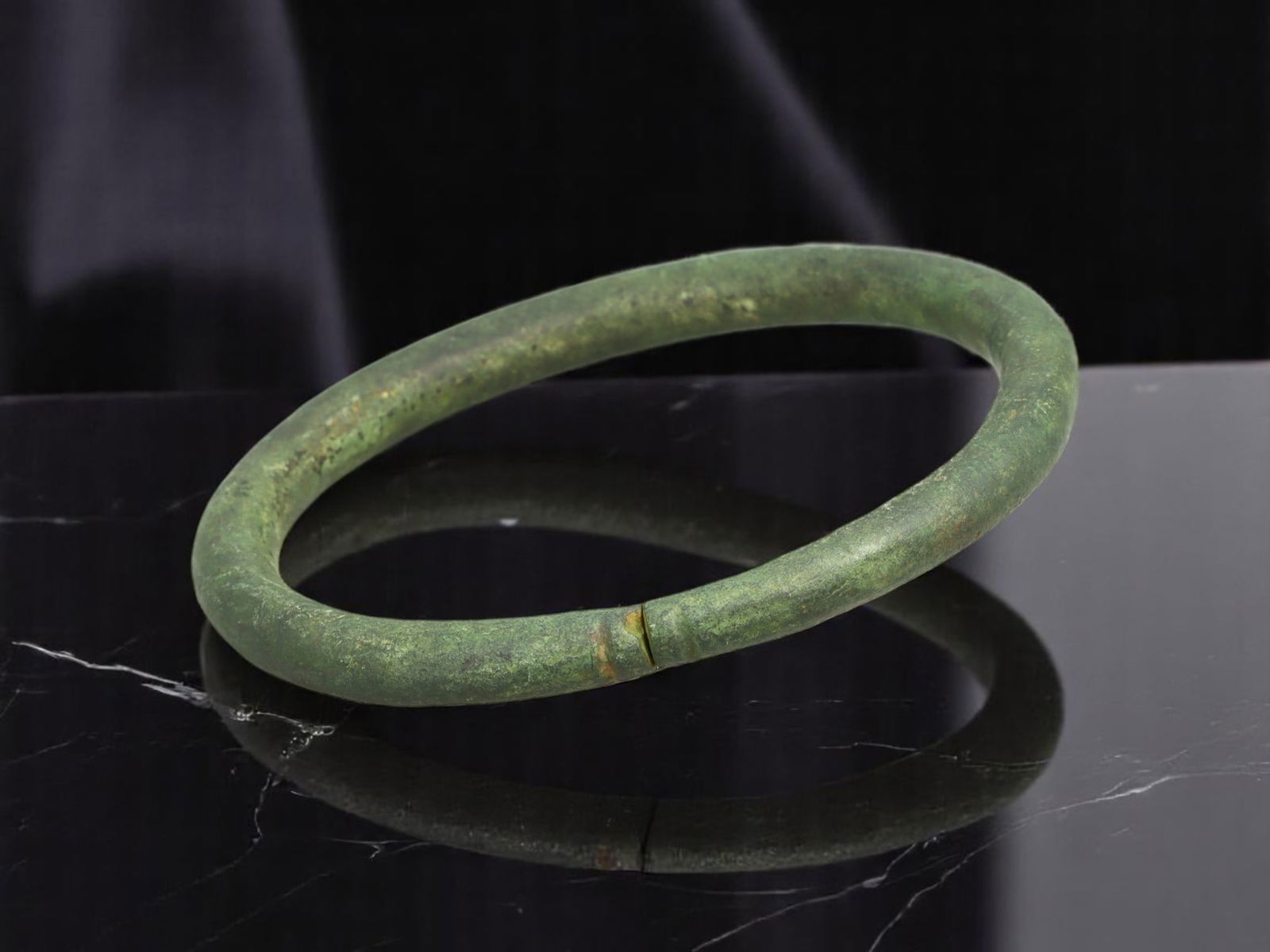LATE ROMAN / EARLY BYZANTINE Offset Ribbed Band Bronze Bracelet, 7.6 cm: Elegant in its restraint, this solid-cast bronze bracelet presents a seamless circular silhouette, punctuated only by a narrow ribbed band offset from center. This understated yet deliberate detail re