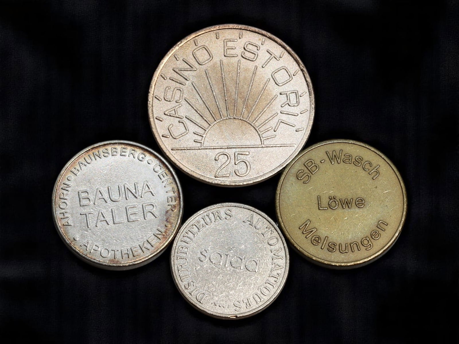 PORTUGAL & GERMANY: Casino, Commerce & Vending - Mixed Token Set, 21-30mm: This versatile four-piece token collection highlights the utilitarian and branded charm of European exonumia. Leading the group is a boldly designed 25-denomination token from Casino Estoril, Portugal