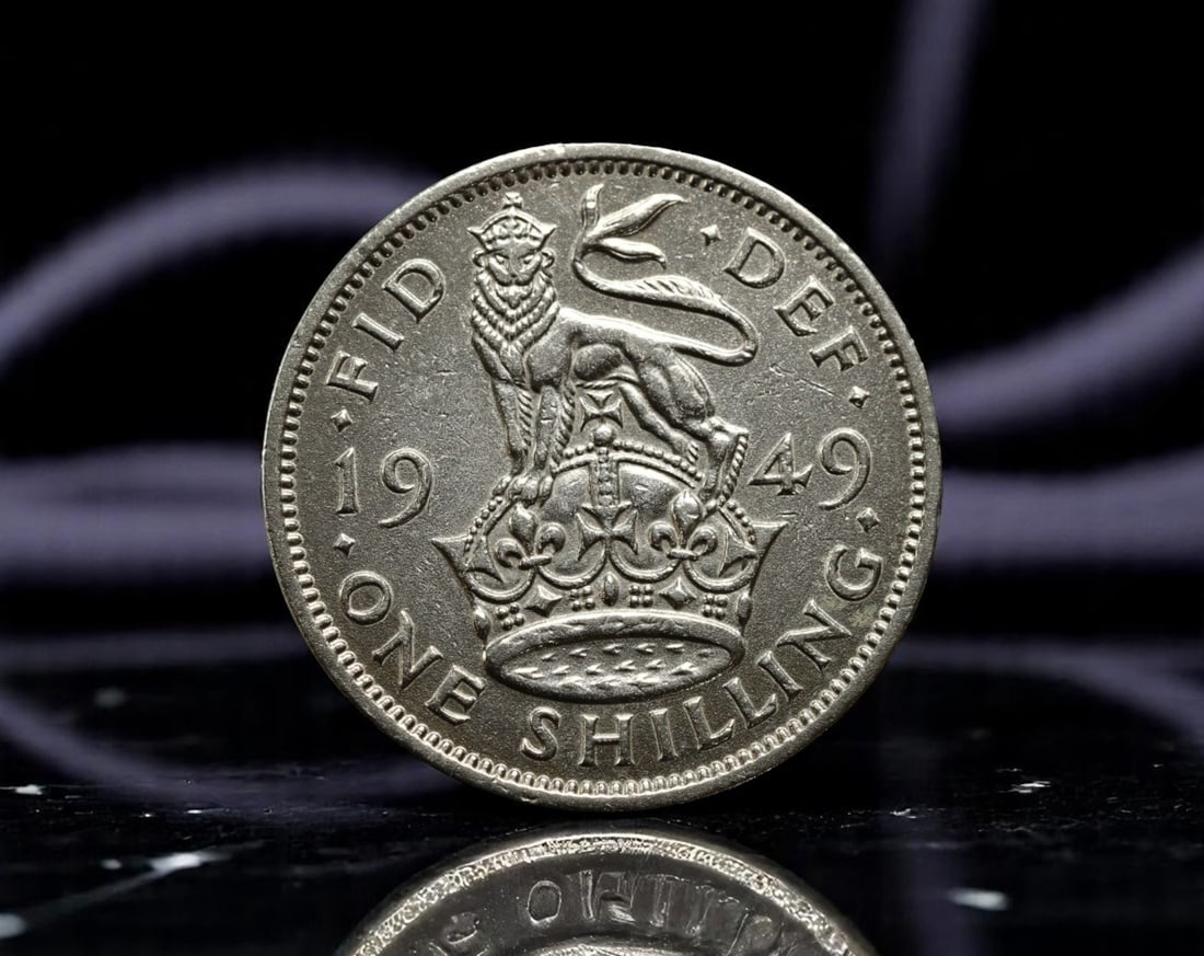 This 1949 'G' mintmark shilling coin encapsulates Britain's resilient monarchy in the post-war era: This 1949 'G' mintmark shilling coin encapsulates Britain's resilient monarchy in the post-war era under King George VI. The crowned English lion stands defiantly atop the royal crown, a heraldic embl