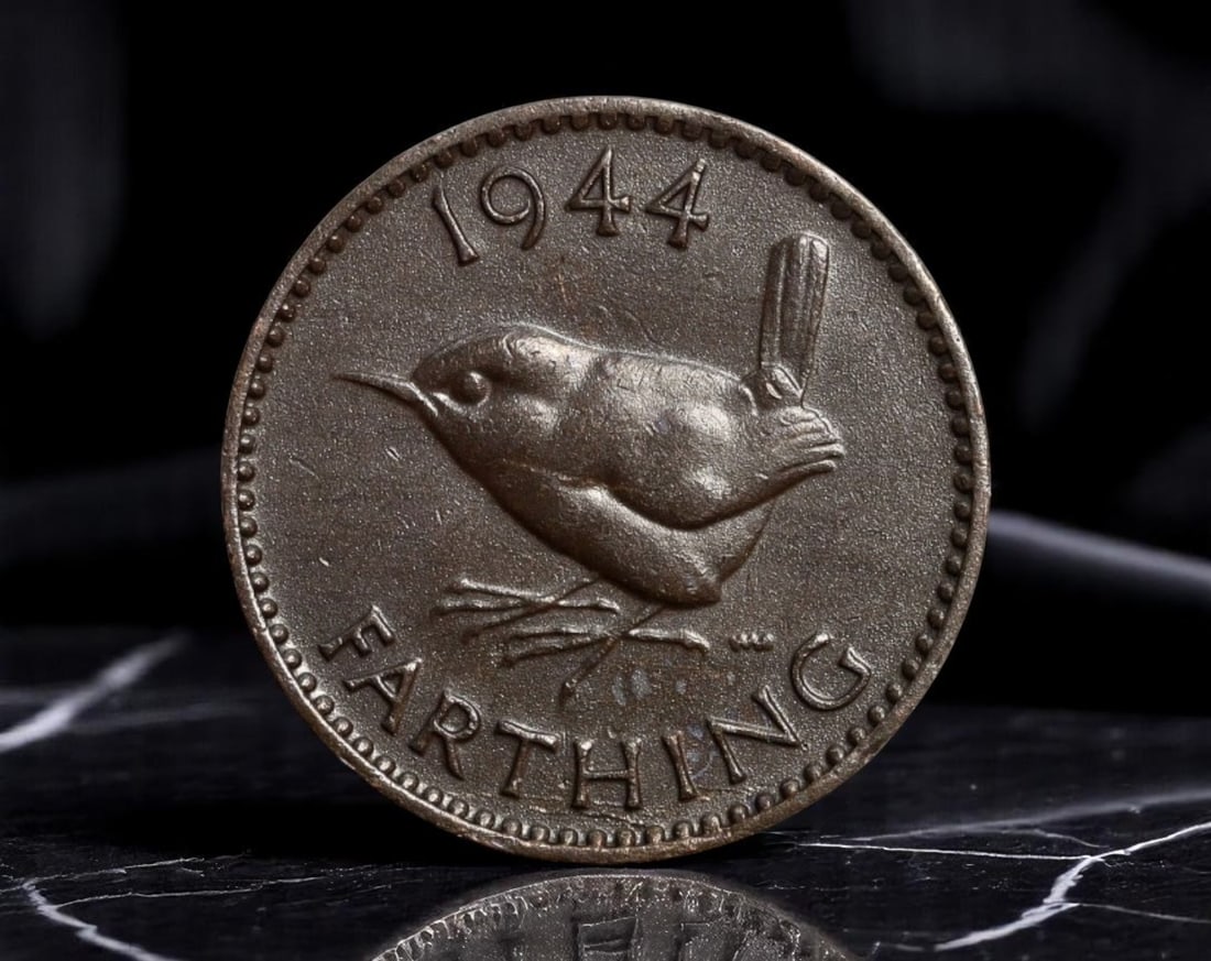 UNITED KINGDOM: Wartime Sovereignty - George VI Farthing Coin, 1944, 20mm: Struck in the throes of World War II, this 1944 farthing embodies Britain's quiet resilience amid global upheaval. The obverse features a dignified profile of King George VI, whose steady leadership d