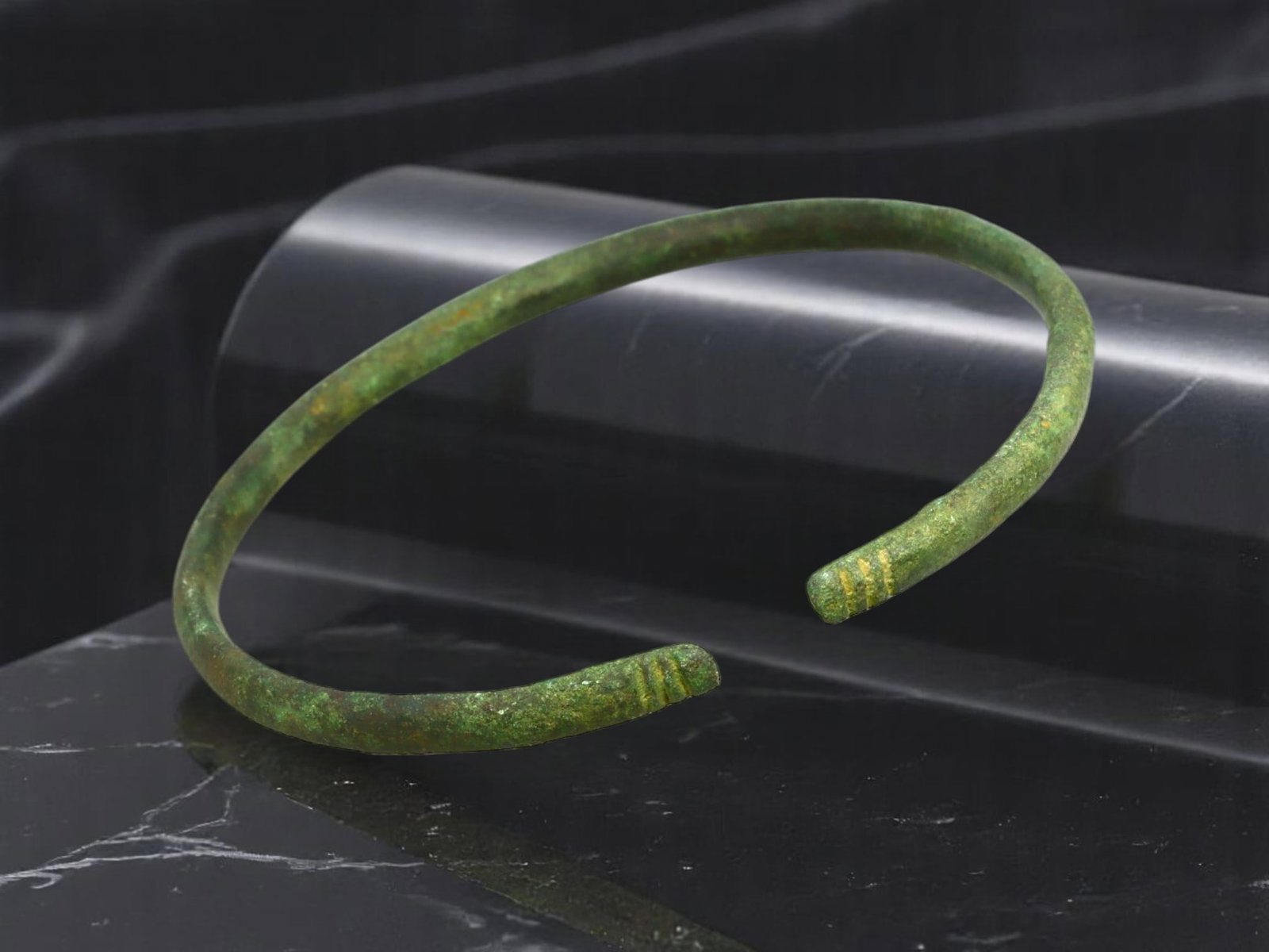 ANCIENT ROMAN PROVINCIAL Open Bangle - Line-Scored Terminals, Green Patina, 6.7 cm: A compelling artifact of Roman-era wearable design, this open bangle features slender proportions with subtly thickened ends, each detailed by incised horizontal lines. Its surface displays a well-dev