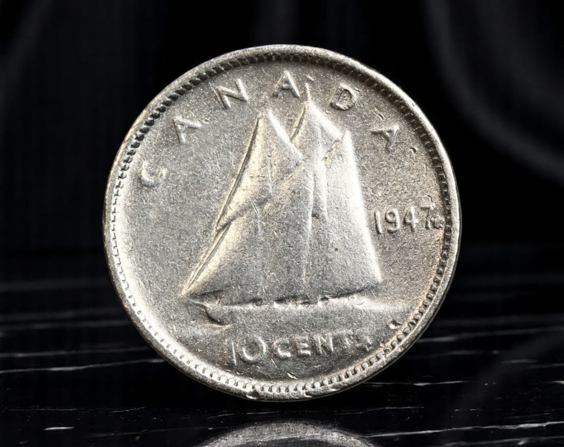 CANADA: George VI - Maritime Heritage Silver 10 Cents Coin, 1947, 18mm: Struck in the early postwar period, this 10 Cents coin offers a vivid homage to Canada's enduring maritime identity. Dominating the design is the iconic Bluenose schooner, rendered in full sail, symbo