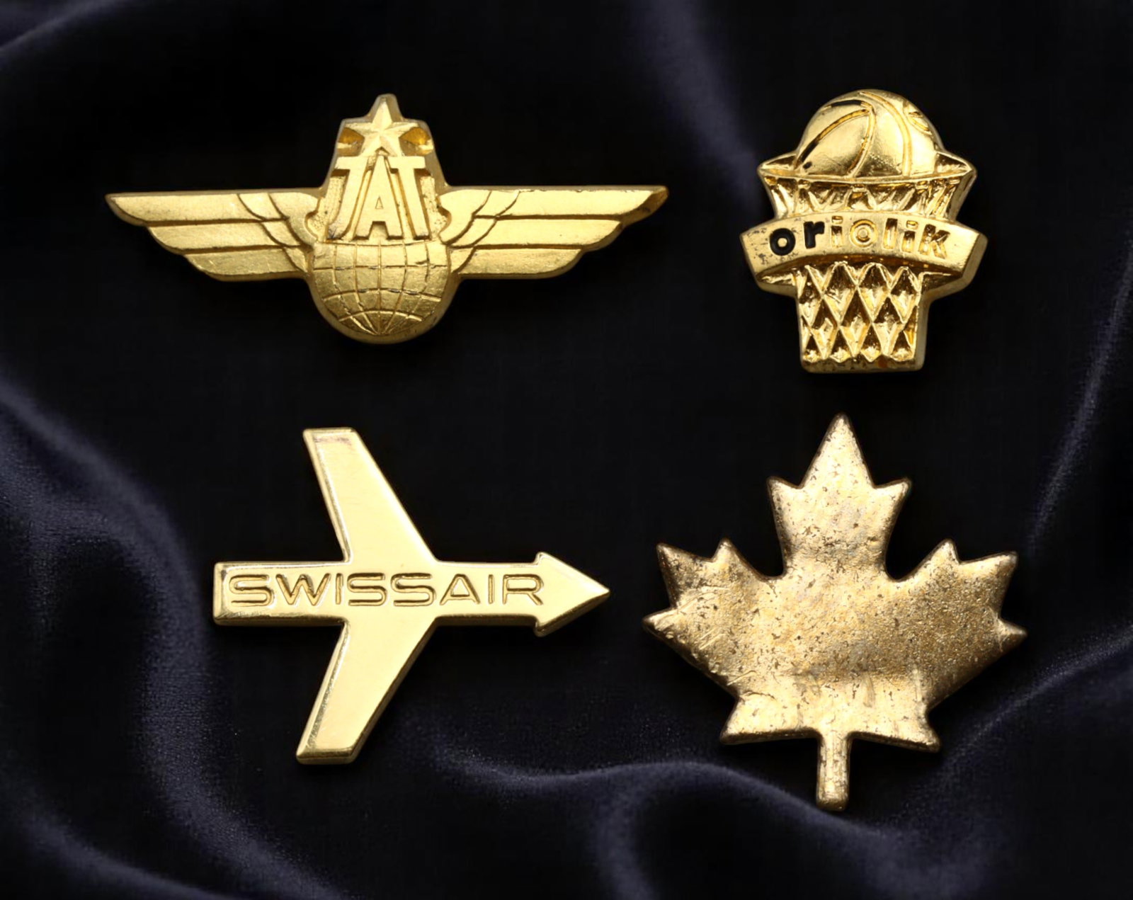Wings of Aviation & Sports Heritage - JAT, Swissair, Oriolik, Canada Pins, mid-20th C, 11-21mm, 4cm: This dynamic set of four golden pins embodies both the golden age of aviation and the spirited culture of international sport. The JAT pin, with its bold wings and globe, commemorates Jugoslovenski Ae