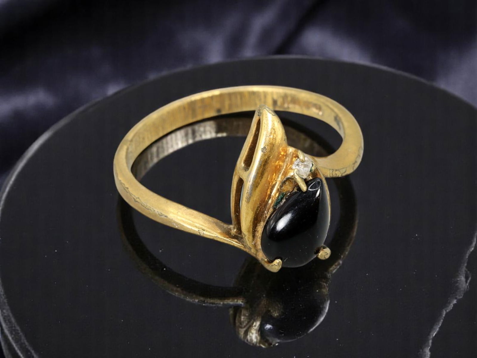 RETRO MODERN Goldtone Ring - Sculptural Black Drop Motif (9.75 US, Stamped TAIWAN): Evoking the drama of late 20th-century studio design, this Retro Modern ring features a fluid, asymmetrical setting with a teardrop-shaped black cabochon and a single clear accent stone. The setting s