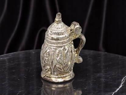 VINTAGE BEER STEIN Charm - Ornate Silvertone Miniature (2.4 cm): A detailed vintage charm modeled after a lidded beer stein, measuring 2.4 cm in silvertone metal with ornate foliate relief and a hinged handle form. The domed lid and engraved sides mimic traditional