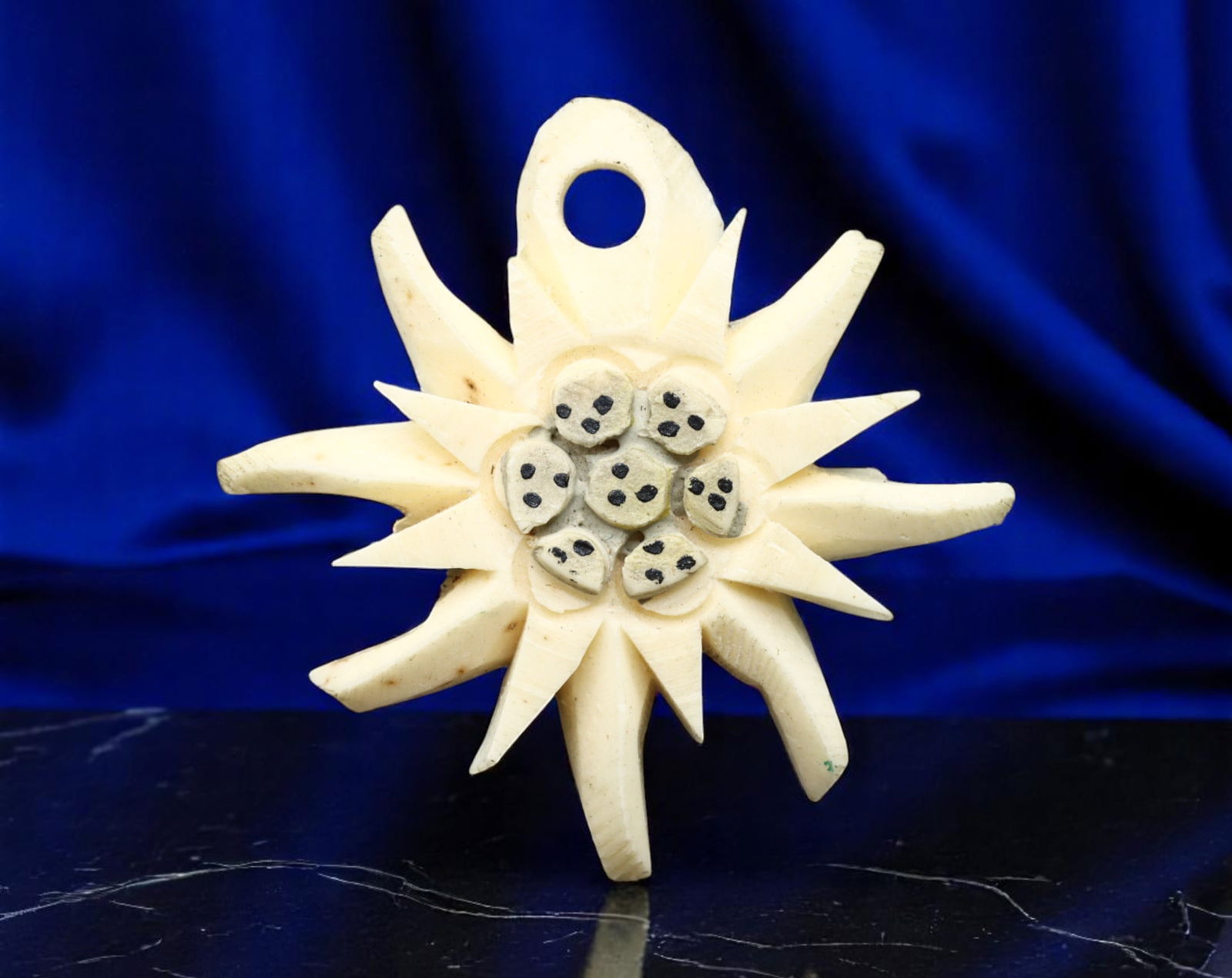 EUROPE: Alpine Heritage - Edelweiss Floral Pendant in Carved Bone, Early 20th Century, 28x25mm: A graceful emblem of mountain identity, this hand-carved edelweiss pendant captures the rustic romance of Alpine tradition. Fashioned from natural bone, the piece features the iconic edelweiss bloom w