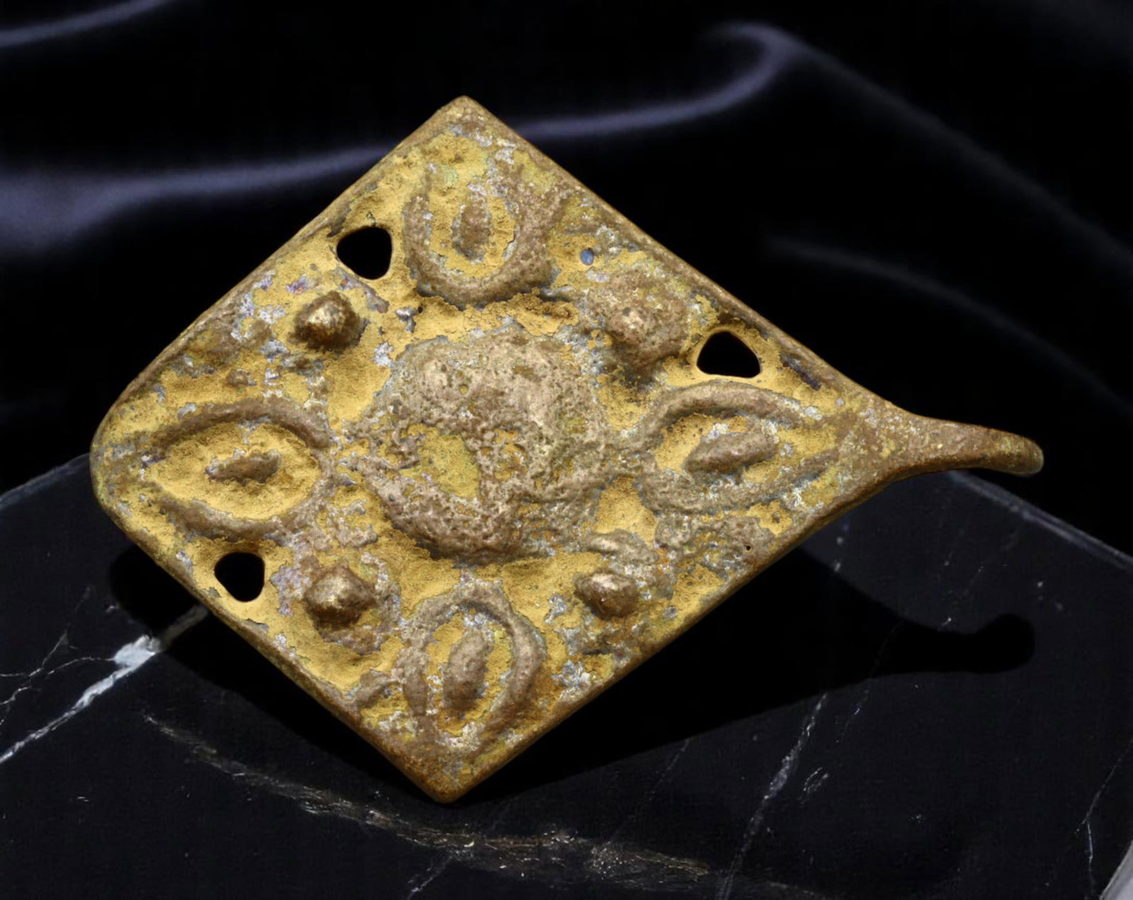 EUROPE: Feudal Command - Medieval Bronze Stirrup Terminal Plate, ca. 12th-14th Century, 38x27mm: A rare survival of equestrian martial culture, this diamond-shaped bronze stirrup terminal plate hails from the chivalric age of medieval Europe. Featuring a bold repousse central boss flanked by styl