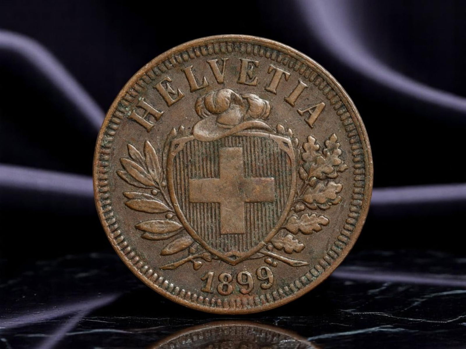SWITZERLAND: Helvetic Confederation - Federal Shield 2 Rappen Coin, 1899, 20mm: Struck in 1899 under the unified banner of the Swiss Confederation, this 2 Rappen coin presents a bold expression of national identity in miniature. The obverse features the iconic Helvetic cross with