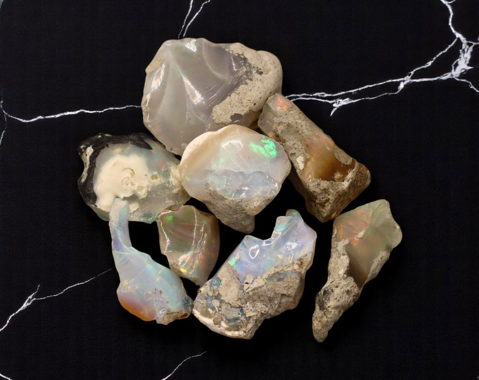 GEM LOT: Ethiopian Welo Opal Rough - Iridescent Play-of-Color in Matrix, Mixed Forms (15g): An estate-sourced parcel of natural Ethiopian Welo Opal rough, totaling 11 grams, this lot features raw, matrix-hosted specimens with vibrant play-of-color across milky, translucent, and honey-toned b