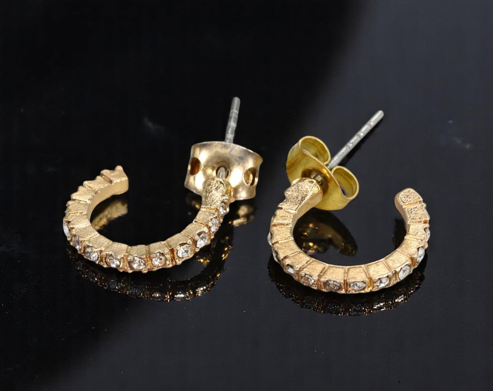 VINTAGE: Half-Hoop Stud Earrings - Textured Goldtone with Channel-Set Clear Stones, 2x1.2cm: Estate Jewelry with structured brilliance, these vintage half-hoop stud earrings showcase segmented goldtone arcs detailed with clear, channel-set stones for a refined sparkle. Measuring 2x1.2cm, the