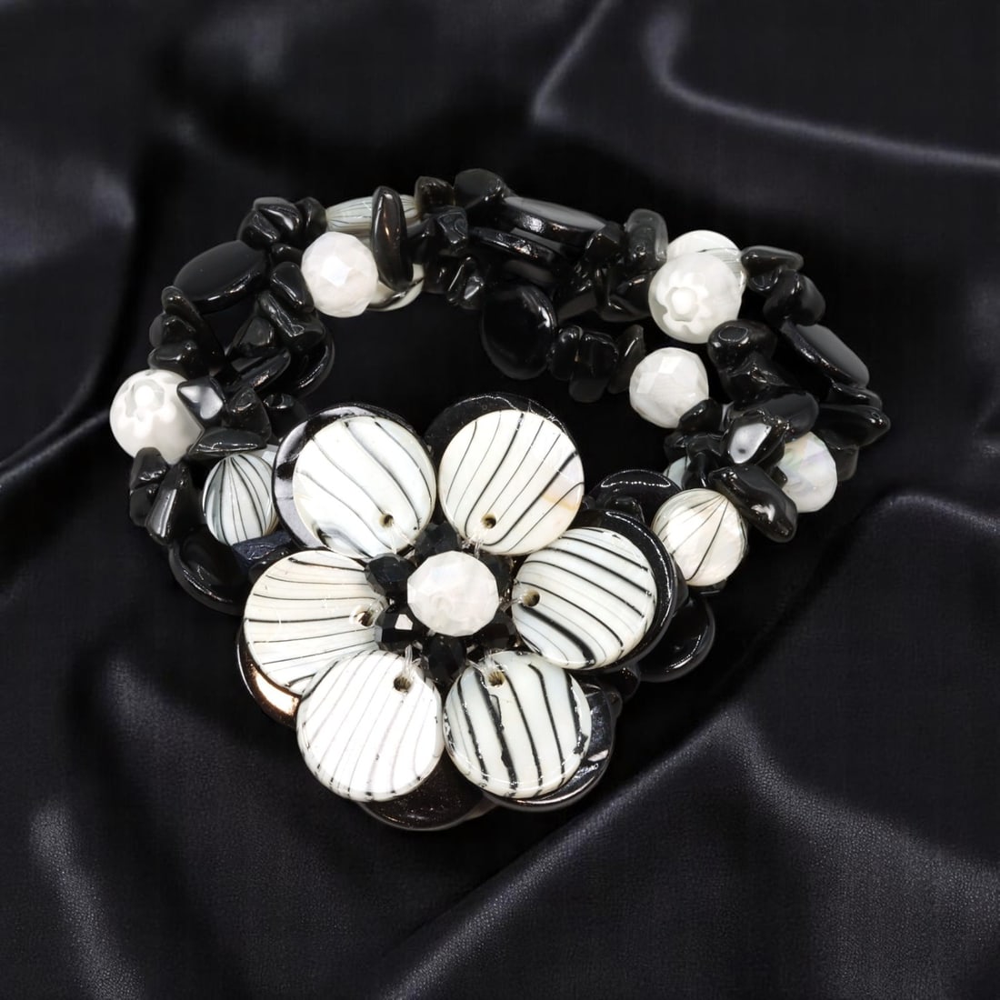 Estate Stretch Bracelet - Black and White Beads with Sculptural Floral Center, 17cm: A unique estate jewelry piece from the late 20th century, this stretch bracelet features an eye-catching mix of polished black and white beads in varying shapes and textures. The focal point is a dram