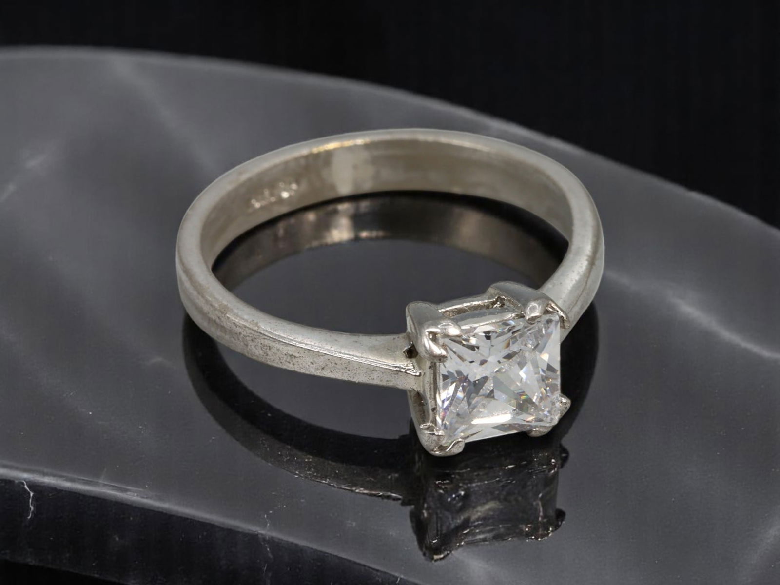 Solitaire Ring - Princess-Cut Brilliant Clear Stone, Stamped 18KRGP, Silvertone (Size 6.5 US): A timeless contemporary solitaire ring featuring a luminous princess-cut brilliant clear stone set in a classic four-prong mount. The sleek silvertone band is stamped "18KRGP" indicating an 18K gold-p