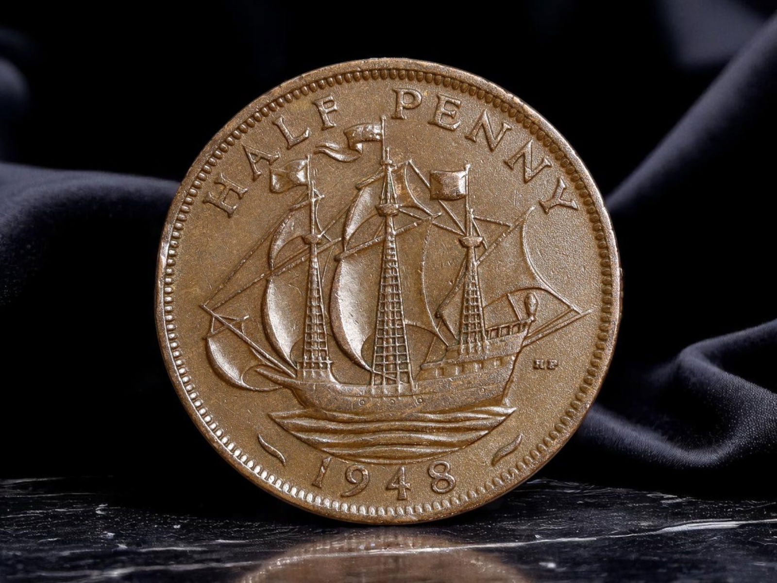 UNITED KINGDOM: George VI - Imperial Maritime Half Penny Coin, 1948, 25mm: Issued in 1948, this half penny coin exemplifies Britain's enduring maritime legacy in the wake of imperial transition. The reverse showcases a meticulously engraved galleon in full sail, evoking the