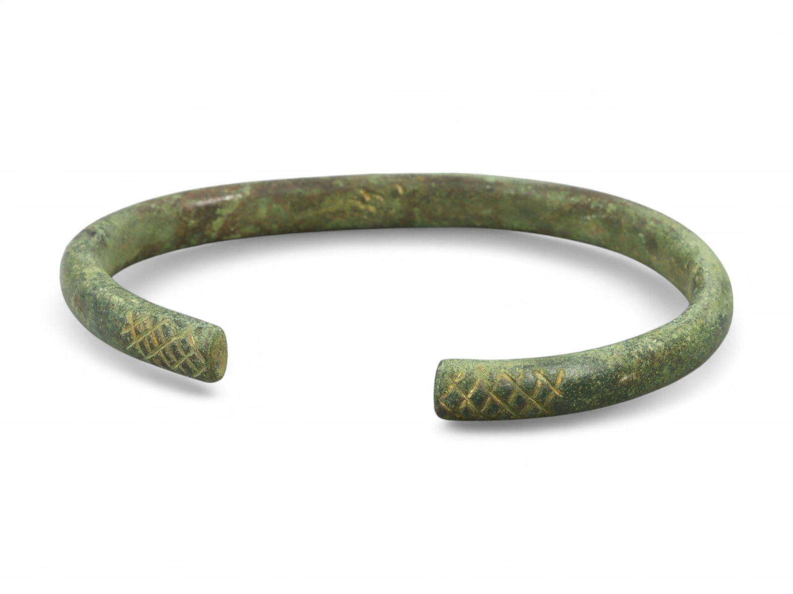 Ancient Celtic Cross-Hatch Terminal Bronze Bracelet, c. 2nd-1st Century BCE: This solid and evocative bronze bracelet, dating to the 2nd-1st century BCE, exemplifies the Celtic artisan's affinity for bold yet refined forms. Crafted in the typical open-cuff style, it features d