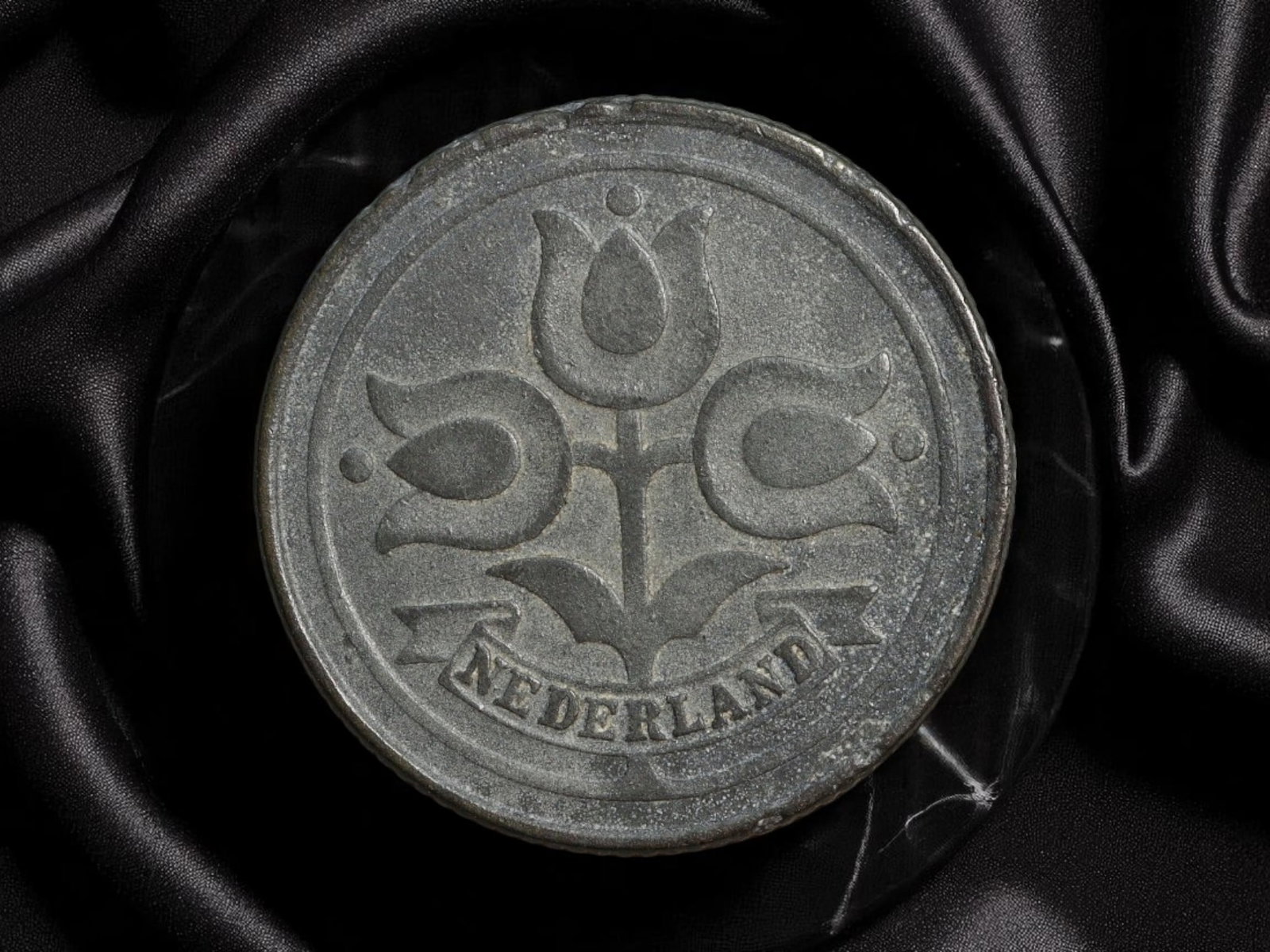 NETHERLANDS: Wartime Occupation - Three Tulips 10 Cent Coin, 1941, 22mm: Issued in 1941 during the German occupation of the Netherlands, this 10 Cent zinc coin embodies both scarcity and symbolic subtlety. The reverse features a stylized cluster of three tulips-delicate ye