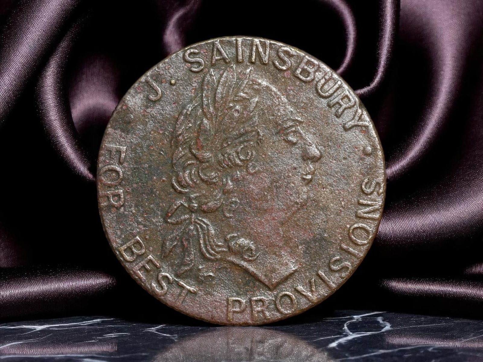 GREAT BRITAIN: George III Era - Sainsbury's Trade Token for Provisions, 1798, 25mm: Issued during the economic turbulence of the late 18th century, this copper token from 1798 captures a remarkable convergence of monarchy, commerce, and civic identity. The obverse bears the laureate 