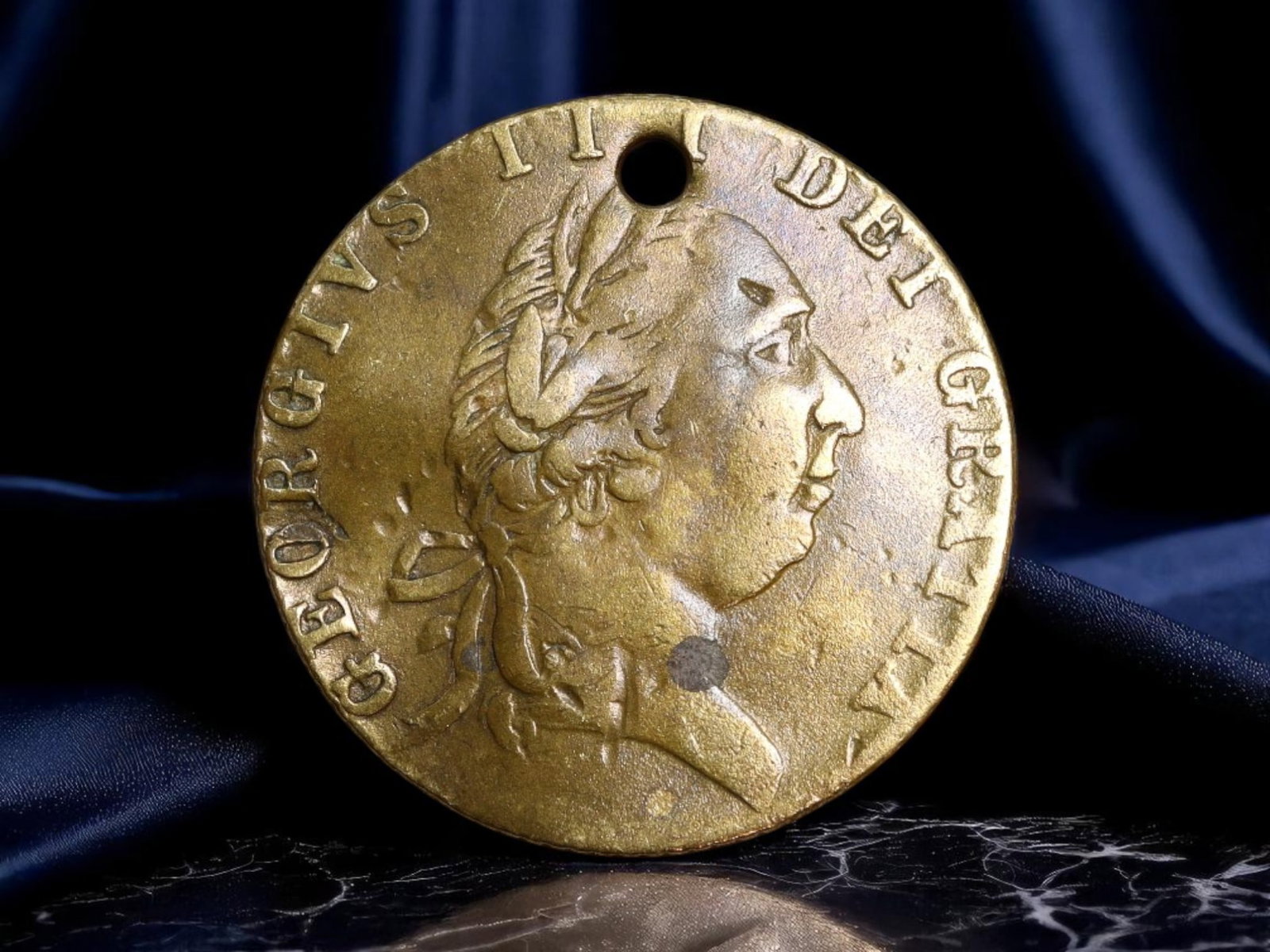 GREAT BRITAIN: George III - Imperial Armorial Jeton, 1790, 20mm: Struck in 1790, this brass jeton from the reign of George III serves as a condensed emblem of imperial sovereignty and heraldic tradition. The obverse presents a laureate bust of the monarch, radiatin