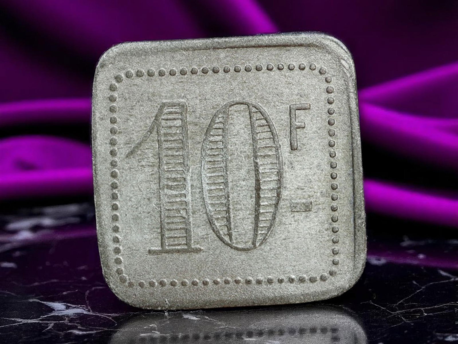 FRANCE: Square Trade Token - 10 Francs Merchant Issue, ND (Undated), 23mm: A minimalist emblem of local commerce, this square-shaped token marked '10 F' on both sides reflects a utilitarian era of French trade where efficiency trumped ornamentation. Framed by a border of rai