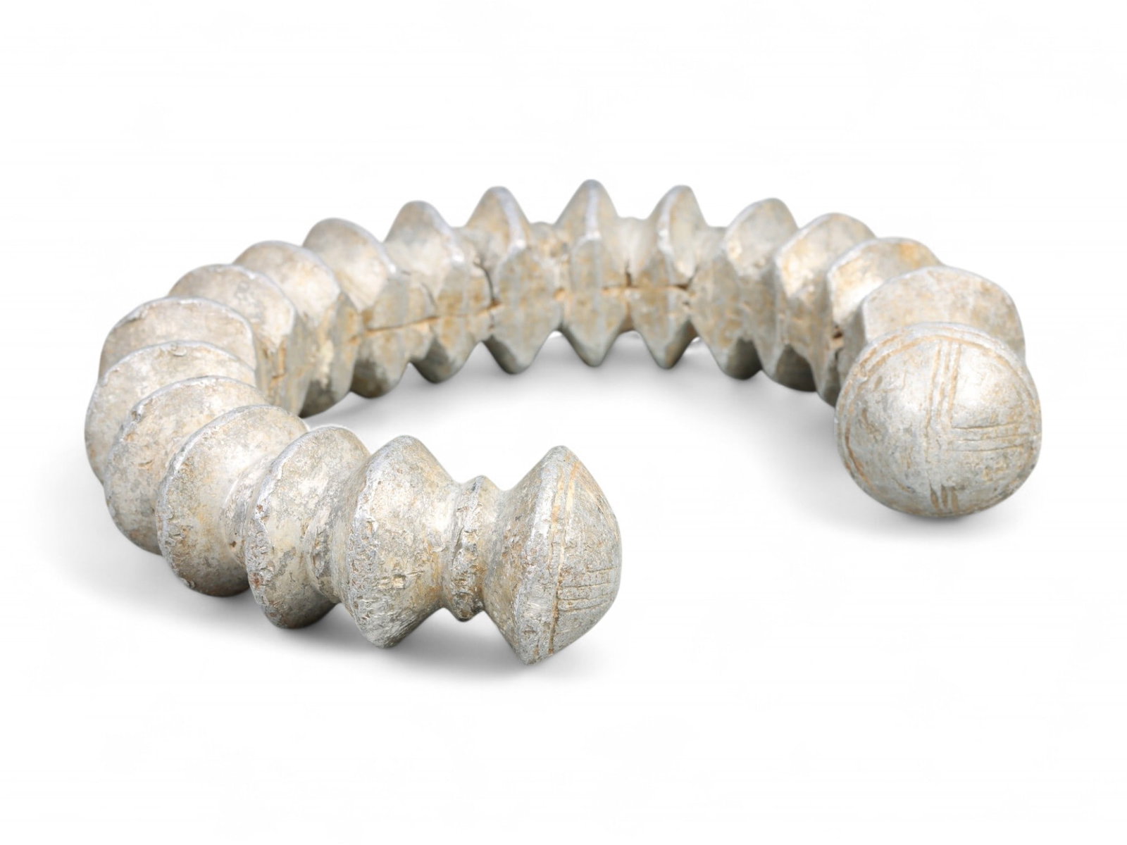 West African Grooved Aluminum Currency Bracelet with Cross-Hatch Terminals, c. 18th-19th Century: This robust and texturally rich bracelet exemplifies West African metal artistry during the 18th-19th century CE. Cast in aluminum-a material revered for its silvery luster and rarity in the pre-indus