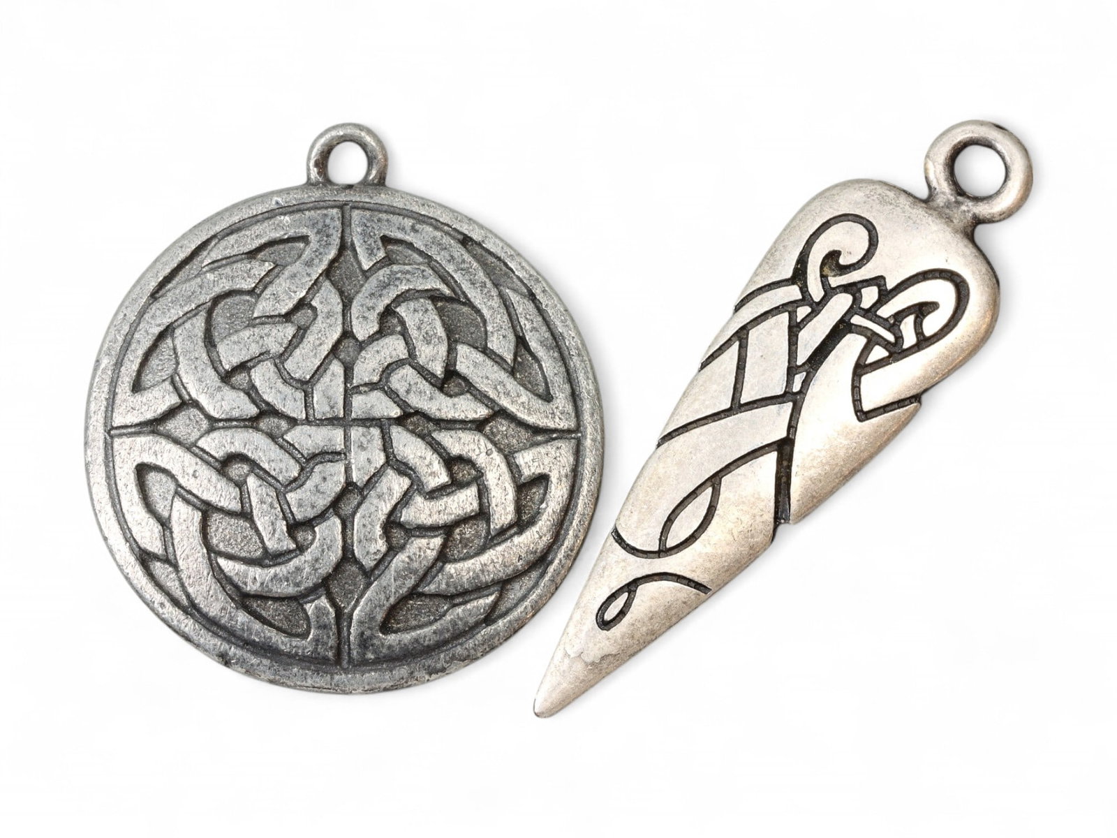 CELTIC REVIVAL Pendant Pair - Knotwork Disc & Zoomorphic Blade Forms (3.2-4.7 cm): This duo of pewtertone pendants channels the spirit of ancient Celtic artistry through stylized geometry and intricate linework. The round pendant (approx. 3.2 cm) features a classic interlaced knot m
