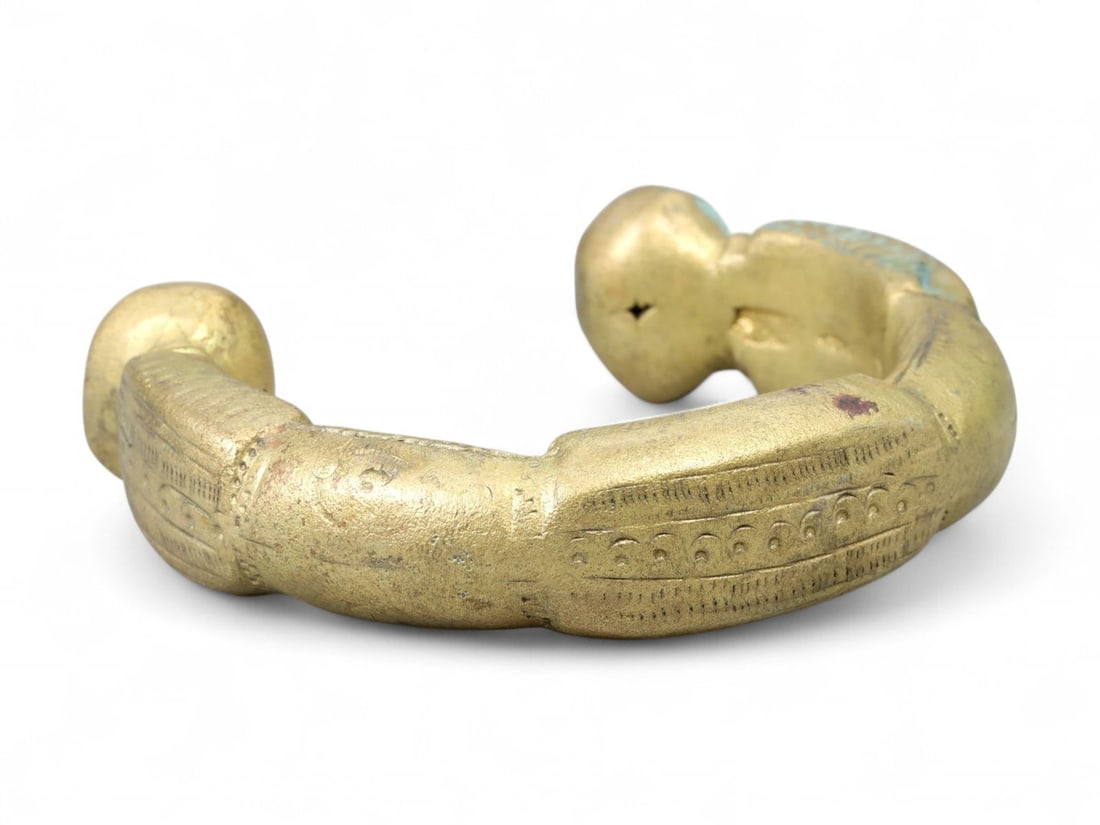 West African Decorated Brass Manilla Bracelet with Geometric Motifs, c. 17th-19th Century CE: This intricately cast brass manilla bracelet, measuring approximately 6.8 cm (2.68 inches) in diameter, is a superb example of Antique West African currency and ornamentation. Featuring broad, rounded