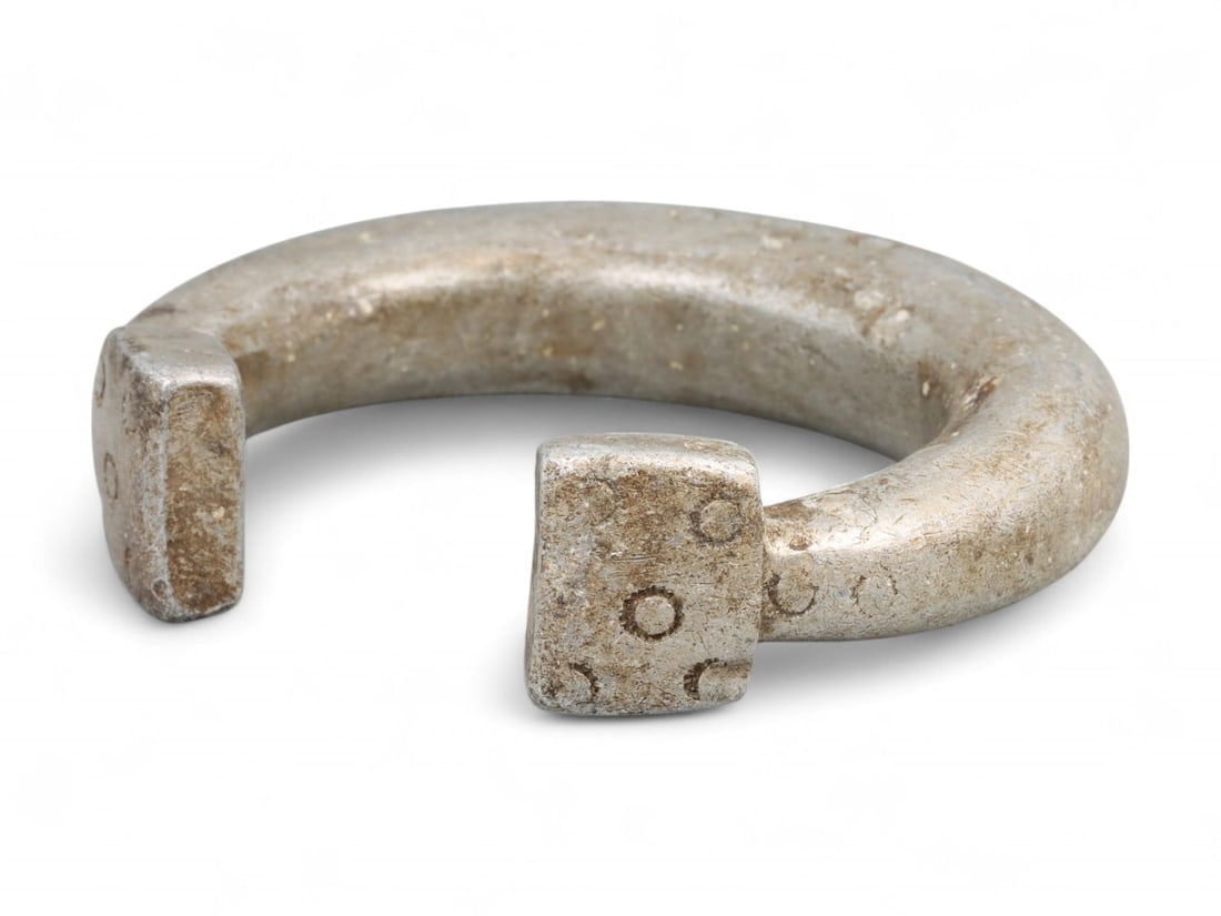 Post-Medieval West African Aluminum Currency Bracelet with Ring-and-Dot Motif, 18th-19th Century CE: This distinctive aluminum bracelet, cast in West Africa during the 18th-19th century, exemplifies the region's merging of ornamentation and exchange economy. Measuring 7.2 cm (2.83 in) in diameter and
