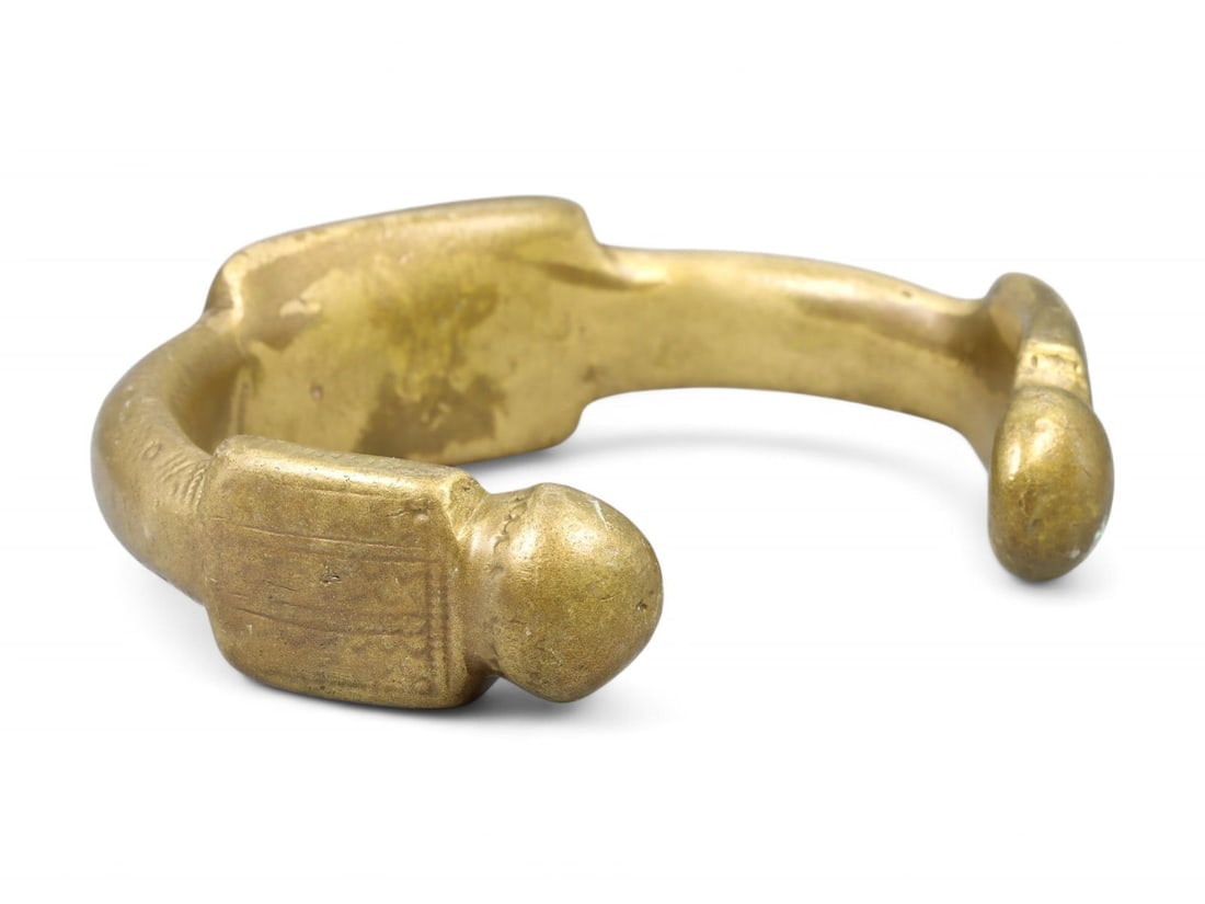 Antique West African Rectilinear Terminal Brass Manilla Bracelet, c. 17th-19th Century CE: Powerful and visually striking, this West African manilla bracelet exemplifies the hybrid of economic function and cultural symbolism central to regional trade from the 17th to 19th centuries. Measuri