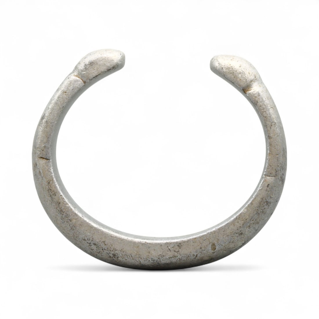 Antique West African Cast Aluminum Trade Bracelet, c. 18th-19th Century CE: This substantial cast aluminum bracelet from West Africa dates to the 18th-19th century CE and was likely used both as adornment and as a form of trade currency. Measuring 7.4 cm, the bracelet is defi
