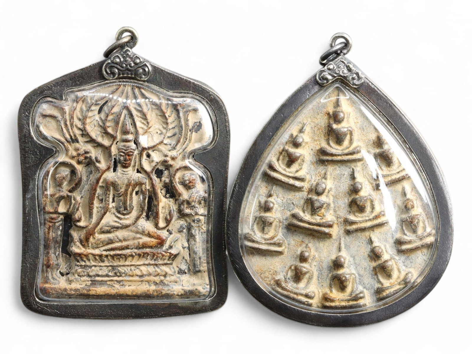 Antique Thai Multi-Buddha and Naga-Guarded Enlightenment Clay Amulet Pair, c. Mid-20th Century, 74g: This captivating pair of Thai sacred amulets embodies two of the most revered iconographies in Theravada Buddhist art: the Naga-Protected Buddha and the Enlightened Assembly motif. Each figure is meti
