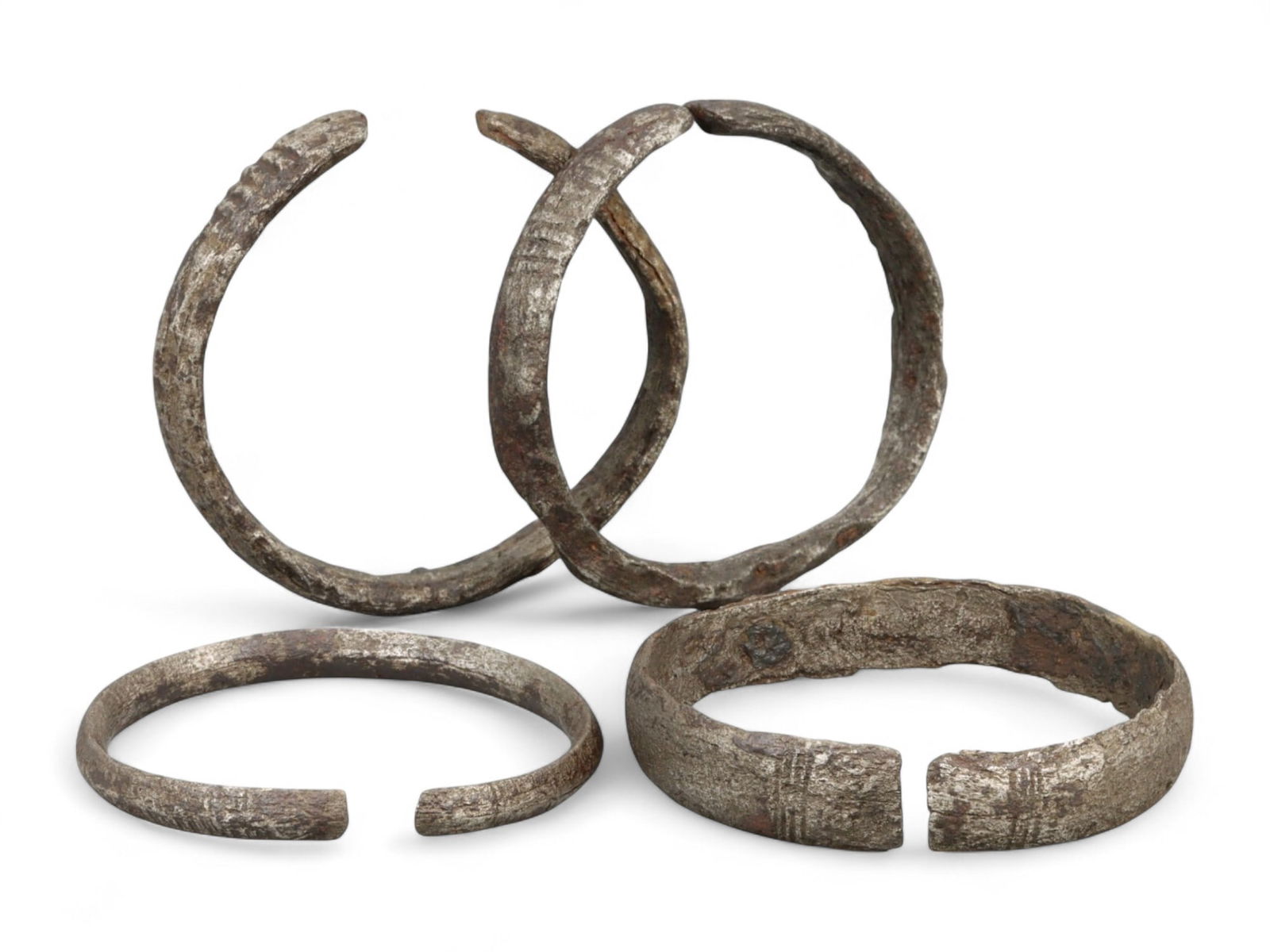 Ancient Medieval Early European Linear-Motif Iron Cuff Bracelet Set, c. 7th-10th Century CE, 110g: This evocative collection of four iron cuff bracelets hails from the Early Medieval period of Europe, dating between the 7th and 10th centuries CE. Emerging from a time of cultural transition followin