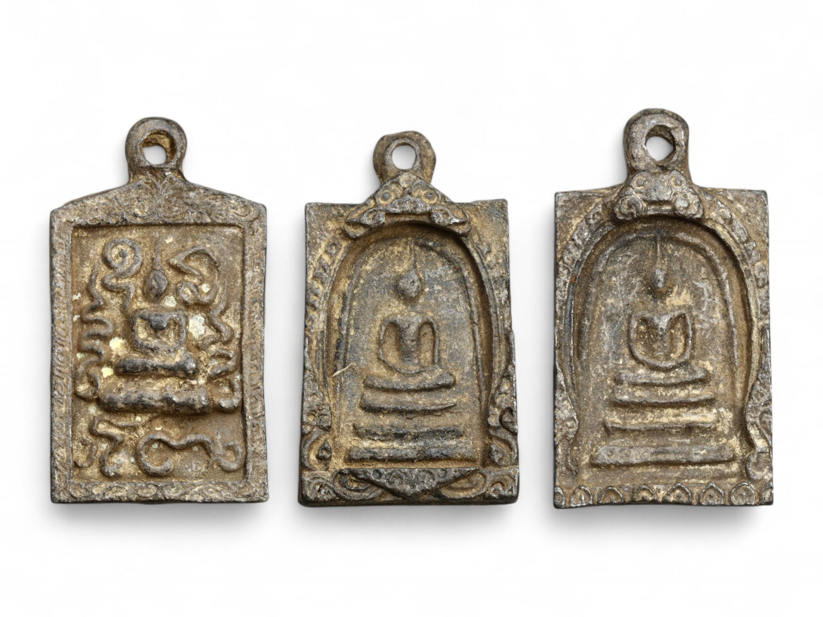 Antique Thai Pendant Amulet Trio, Script & Seated Buddha Motifs, 114g: This intriguing set of three antique Thai Buddhist pendant amulets, cast in lead alloy and measuring 4.5 to 5 cm in height, offers a harmonious blend of devotional imagery and sacred script. Weighing 