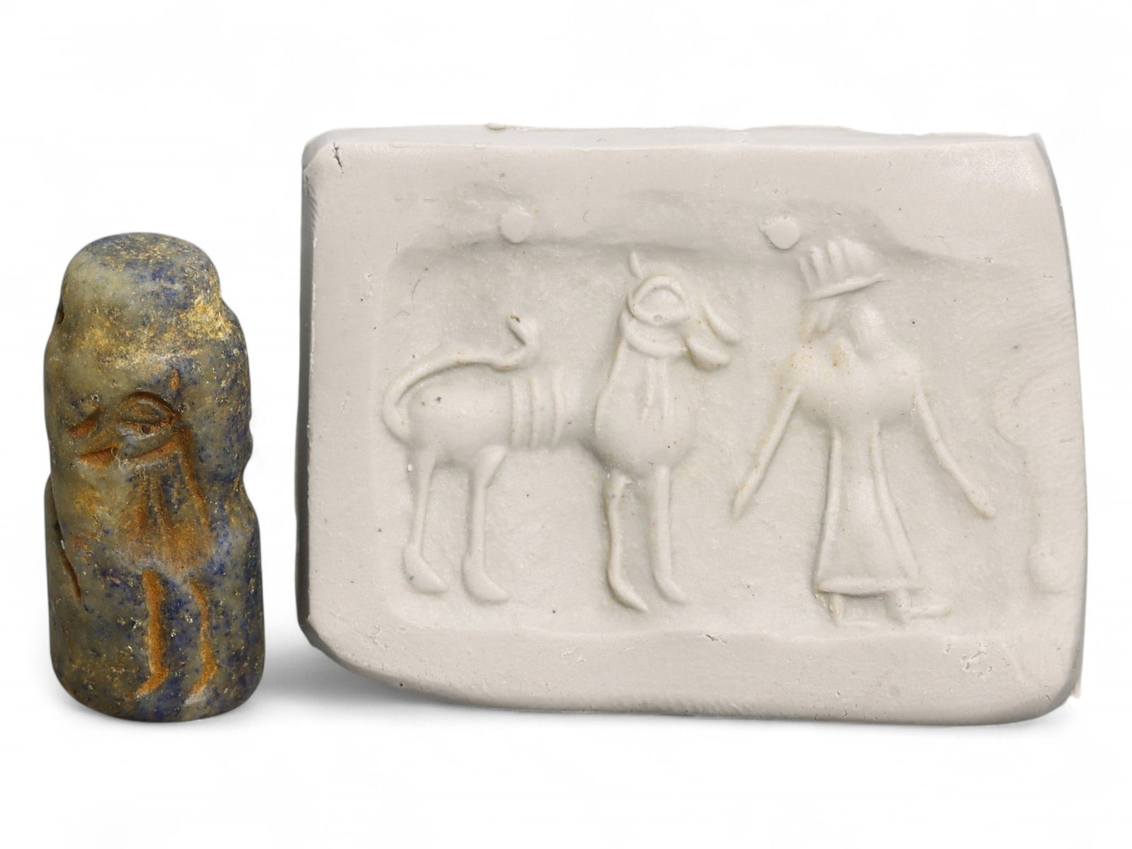 Ancient Akkadian Worshipper and Sacred Animal Lapis Lazuli Cylinder Seal, c. 2350-2150 BCE, 8g: This compact yet evocative Akkadian cylinder seal, carved from veined lapis lazuli, presents a serene ritual tableau: a robed worshipper approaches a large horned animal-likely a sacred goat or bull-b