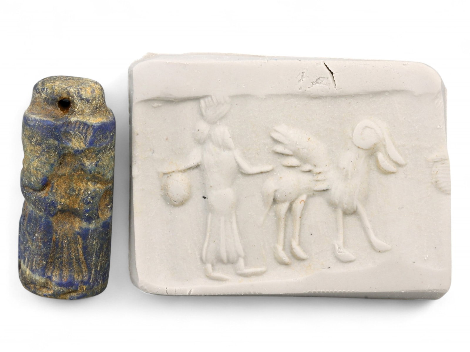 Ancient Mesopotamian Winged Ram & Attendant Lapis Lazuli Cylinder Seal, c. 2nd Millennium BCE, 9g: This richly detailed cylinder seal, carved from celestial-blue lapis lazuli, features a remarkable scene: a robed human figure, possibly a priest or dignitary, approaches a fantastical winged ram. Mea