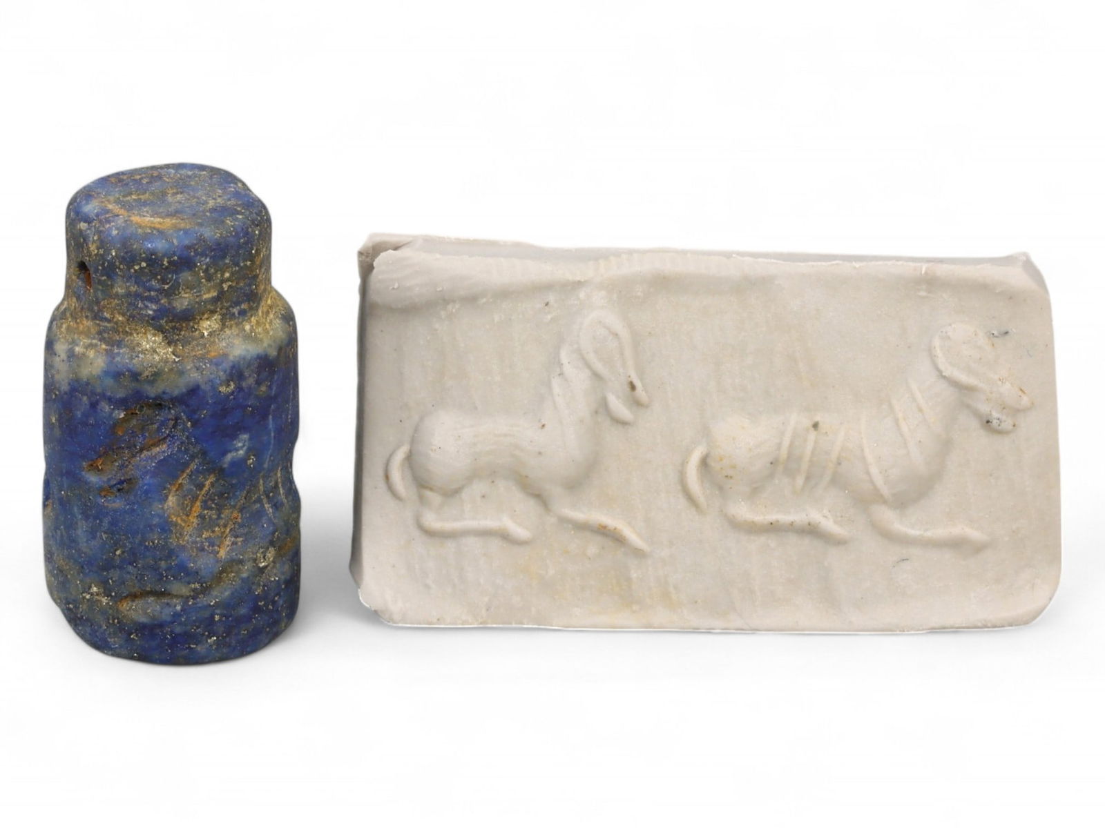 Ancient Akkadian Dual Reclining Ram Cylinder Lapis Lazuli Seal, c. 2350-2150 BCE, 7.2g: This finely preserved lapis lazuli cylinder seal, dating from the Akkadian Empire (c. 2350-2150 BCE), depicts a harmonious scene of two reclining rams positioned in mirrored repose. With their coiled