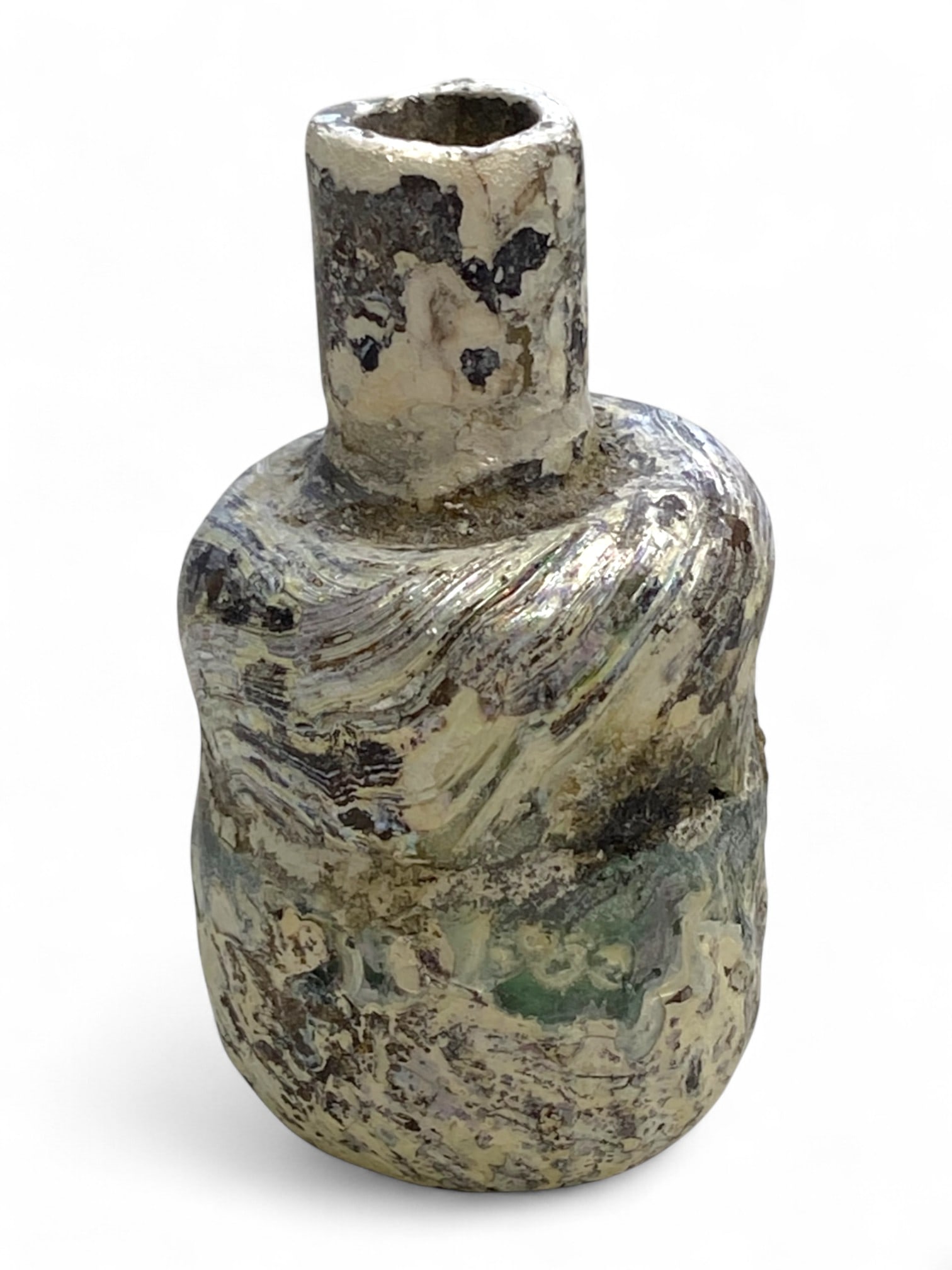 Ancient Roman Iridescent Swirled Glass Unguentarium Bottle, c. 1st-3rd Century CE, 50g: This delicate and richly patinated Roman glass unguentarium-used for holding precious oils, perfumes, or medicinal salves-dates to the 1st-3rd century CE. Measuring 7 cm (2.75 inches) in height and we