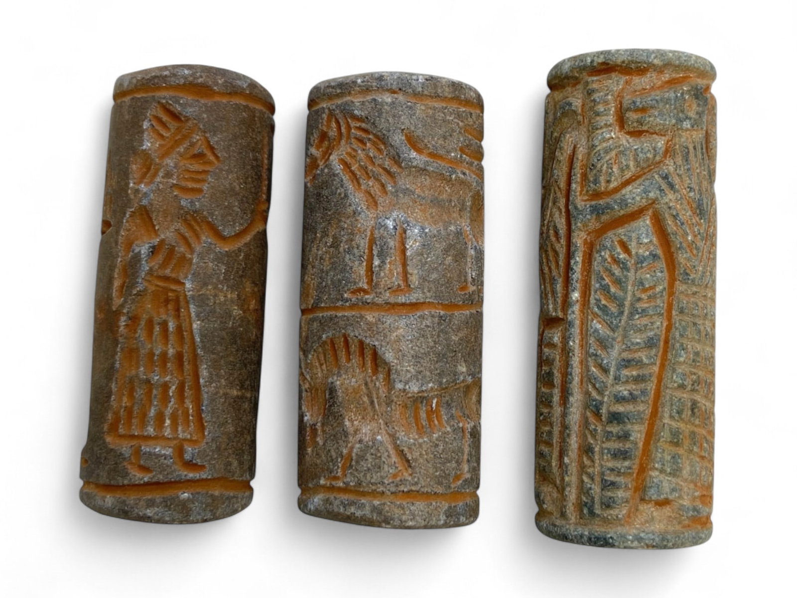Antique Near Eastern Revivalist Steatite Cylinder Seals Depicting Mythical and Faunal Motifs, 101g: This compelling trio of antique cylinder seals, carved from dark steatite with burnt-orange highlights, offers a vivid reimagining of Mesopotamian iconography through a 19th- to early 20th-century rev