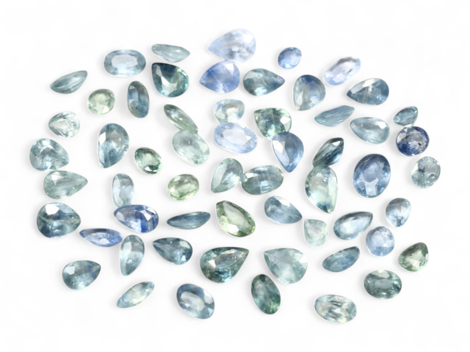 15.94 Carats Blue-Green Sapphire Mix - Natural Sri Lankan Selection: This alluring 15.94 carat selection of faceted sapphires captures a refined spectrum of tranquil blue and soft green tones. Each stone exhibits subtle shifts in color, with some leaning toward icy cor
