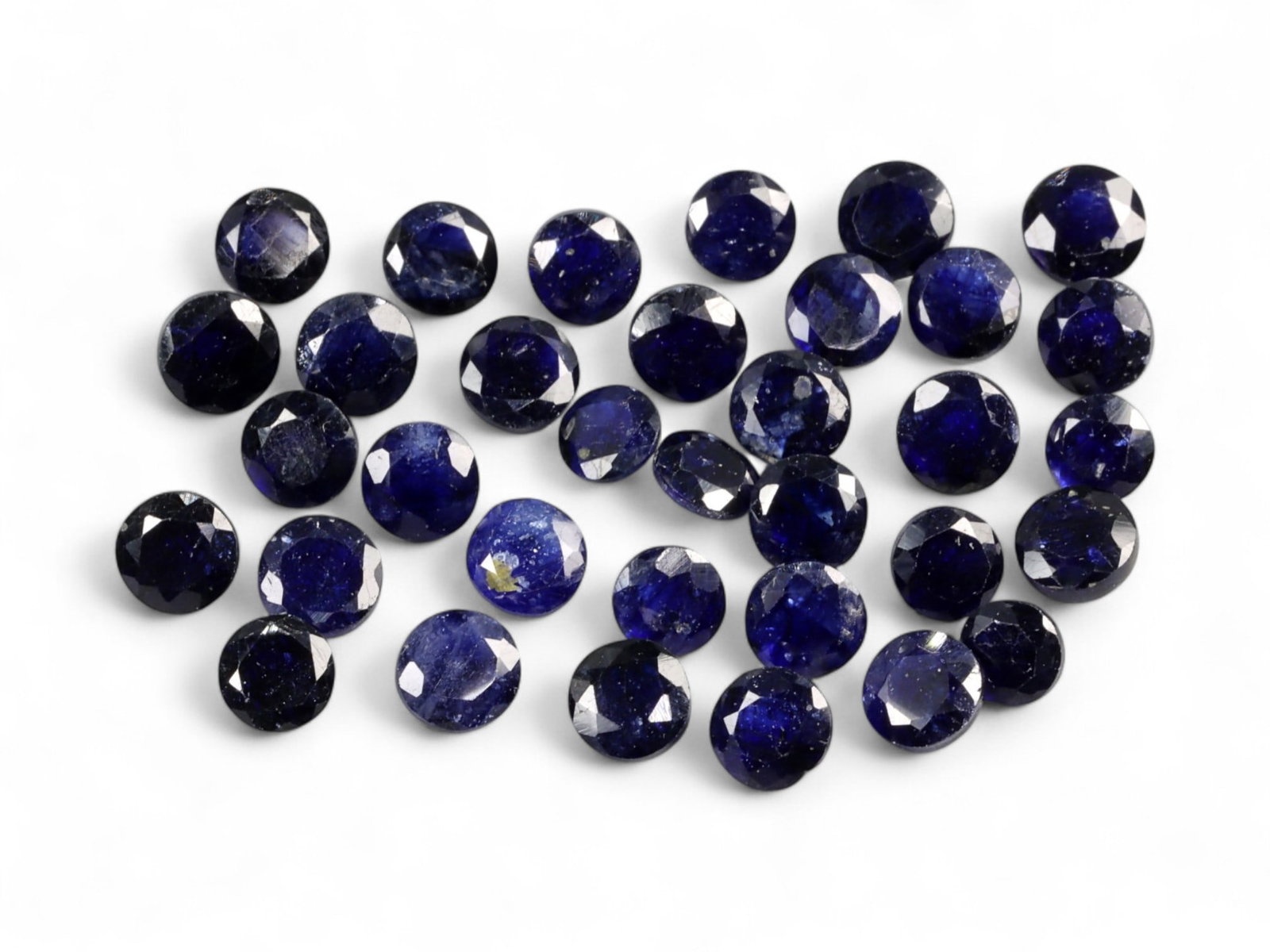 24.95 Carats Midnight Blue Sapphire Parcel - Natural Ceylon Stones: This striking parcel of round-cut sapphires exhibits a deep midnight blue hue, laced with subtle flashes of indigo and inky violet under light. The stones feature a classic dome cut with lively facets