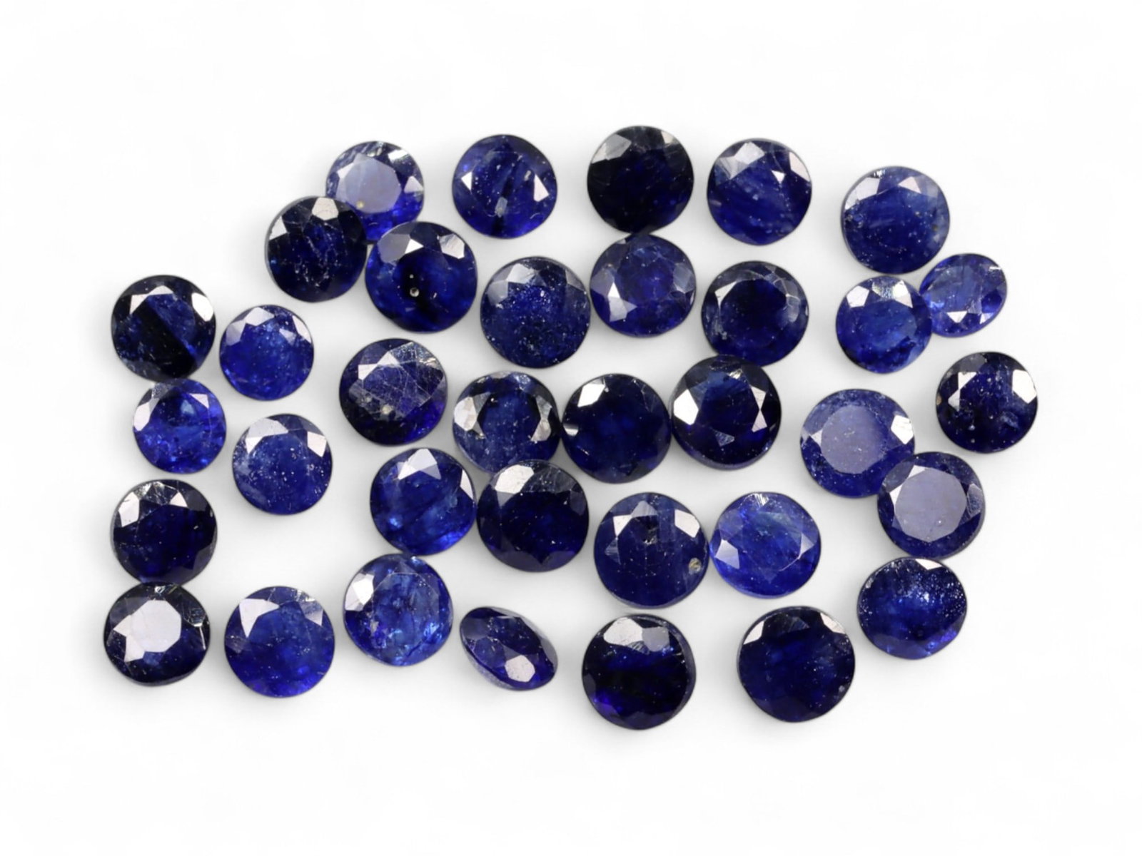24.60 Carats Midnight Blue Sapphire Parcel - Natural Ceylon Stones: This striking parcel of round-cut sapphires exhibits a deep midnight blue hue, laced with subtle flashes of indigo and inky violet under light. The stones feature a classic dome cut with lively facets
