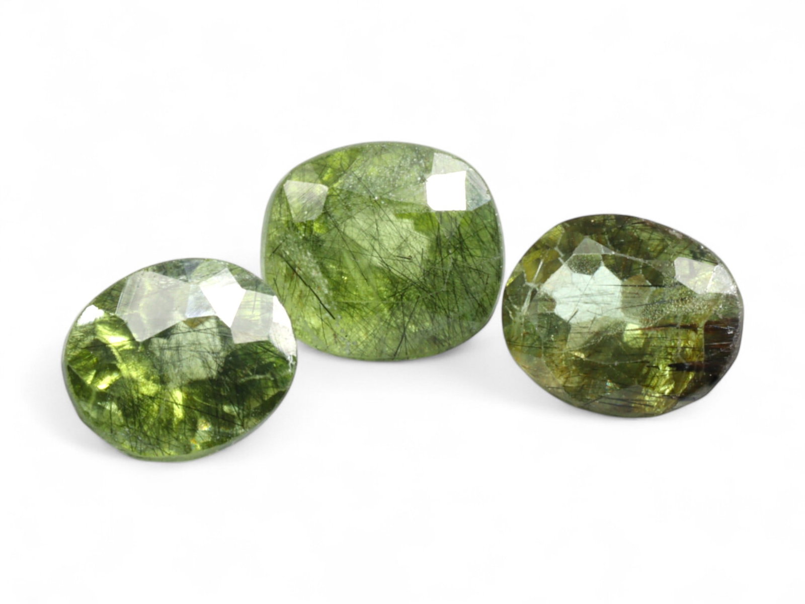 7.75 Carats Olive Green Rutilated Peridot Trio - Natural Pakistani Stones: This striking trio of olive green peridot gems is uniquely defined by internal needle-like inclusions, creating a dramatic interplay between gemstone clarity and rutile-style texture. Each faceted ova
