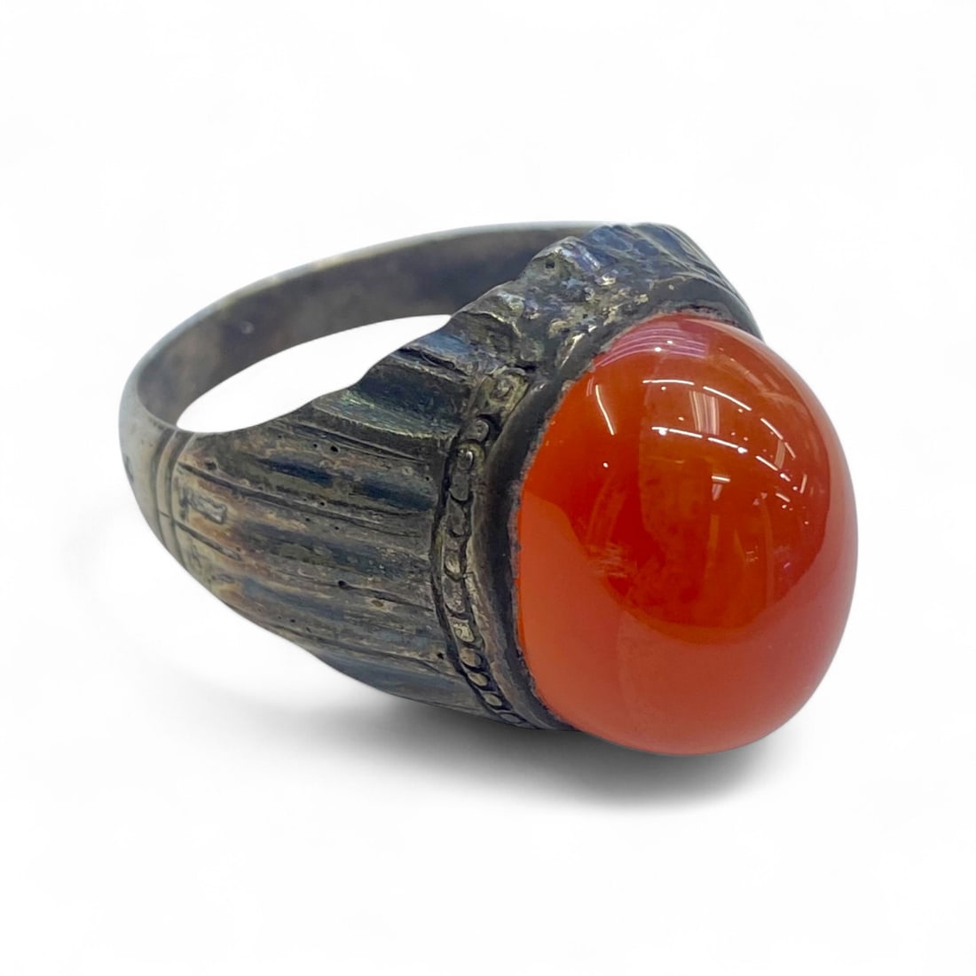 Antique Silver Ring with Striking Orange-Red Carnelian Cabochon, c. Early-Mid 20th Century, 12g: This bold antique silver ring features a luminous, high-domed orange-red carnelian cabochon, radiating warmth and vitality. The stone is set within an ornate bezel framed by fine dotted and ridged det