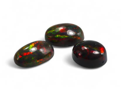 6.01 Carats Black Smoked Welo Opal Cabochon Lot - Natural Ethiopian Stones: This striking trio of black smoked Welo opals exhibits an intense play-of-color, with flashes of fiery red, neon green, and golden orange dancing vividly against their deep, smoky base. The cabochon c